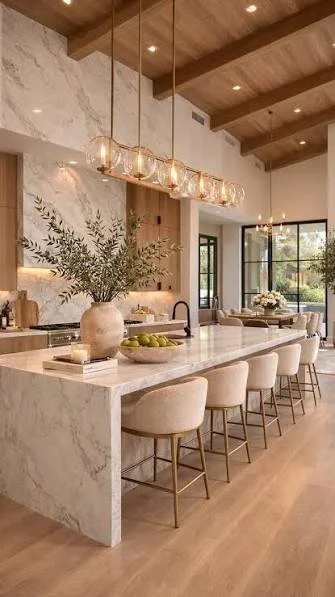 Modern kitchen with marble island, beige stools, pendant lights, wooden ceiling, large windows, and outdoor view.