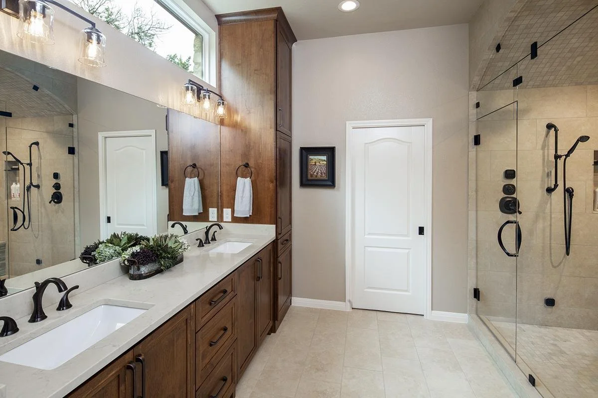 Bathroom renovation in DFW by Gold Oak Remodeling with double vanity, black fixtures, and glass-enclosed shower design.