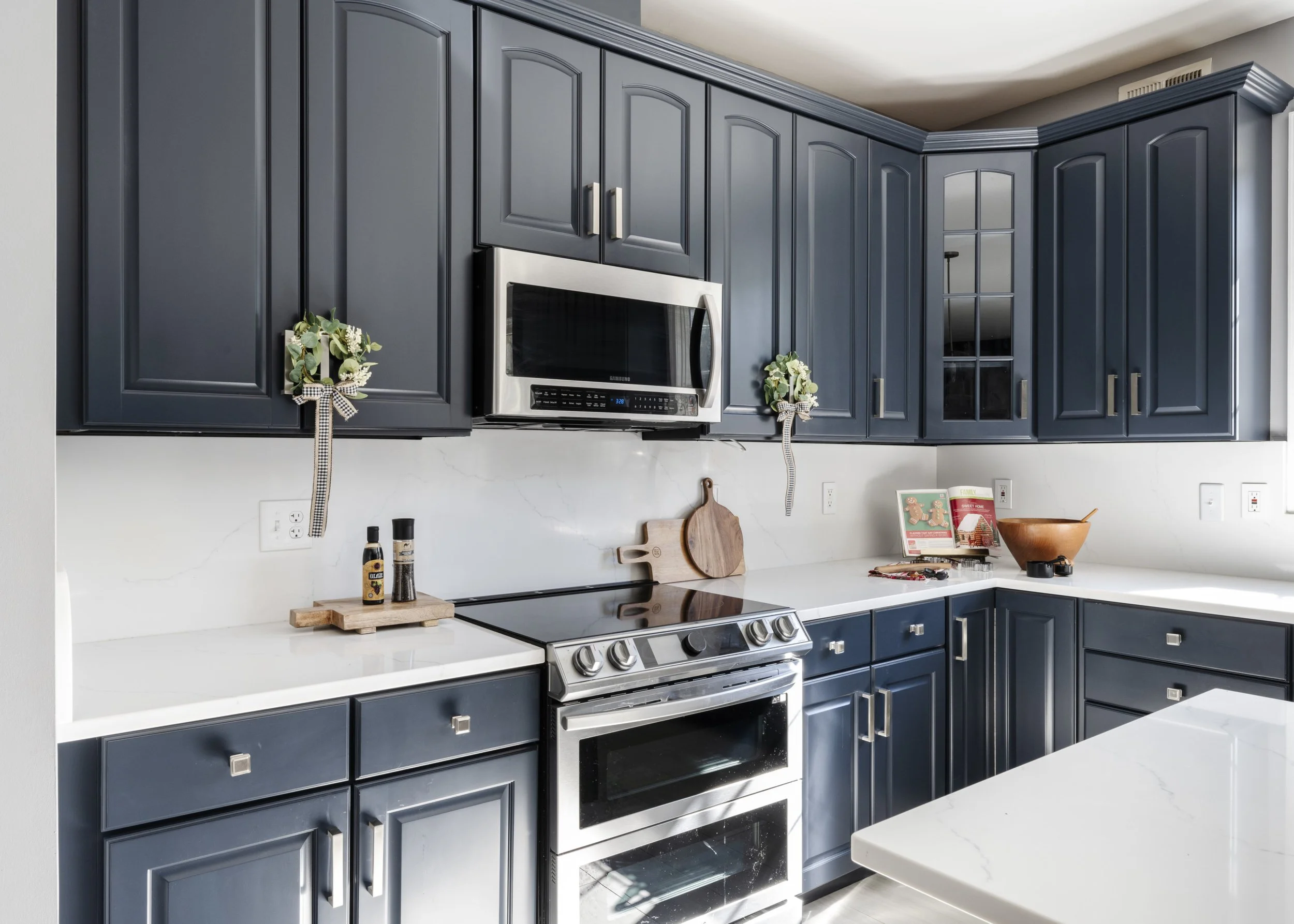 Kitchen with deep blue cabinetry, white countertops and stainless steel appliances