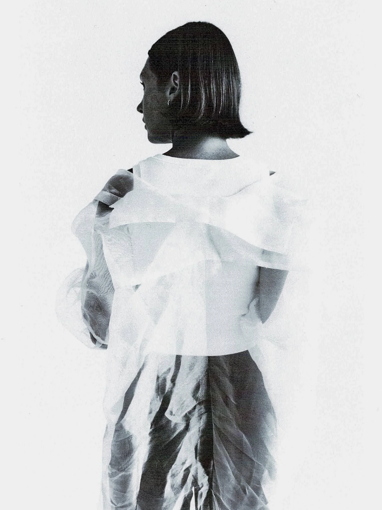 A person dressed in martial arts attire, with a waist-up view, standing against a plain, light background, facing left.