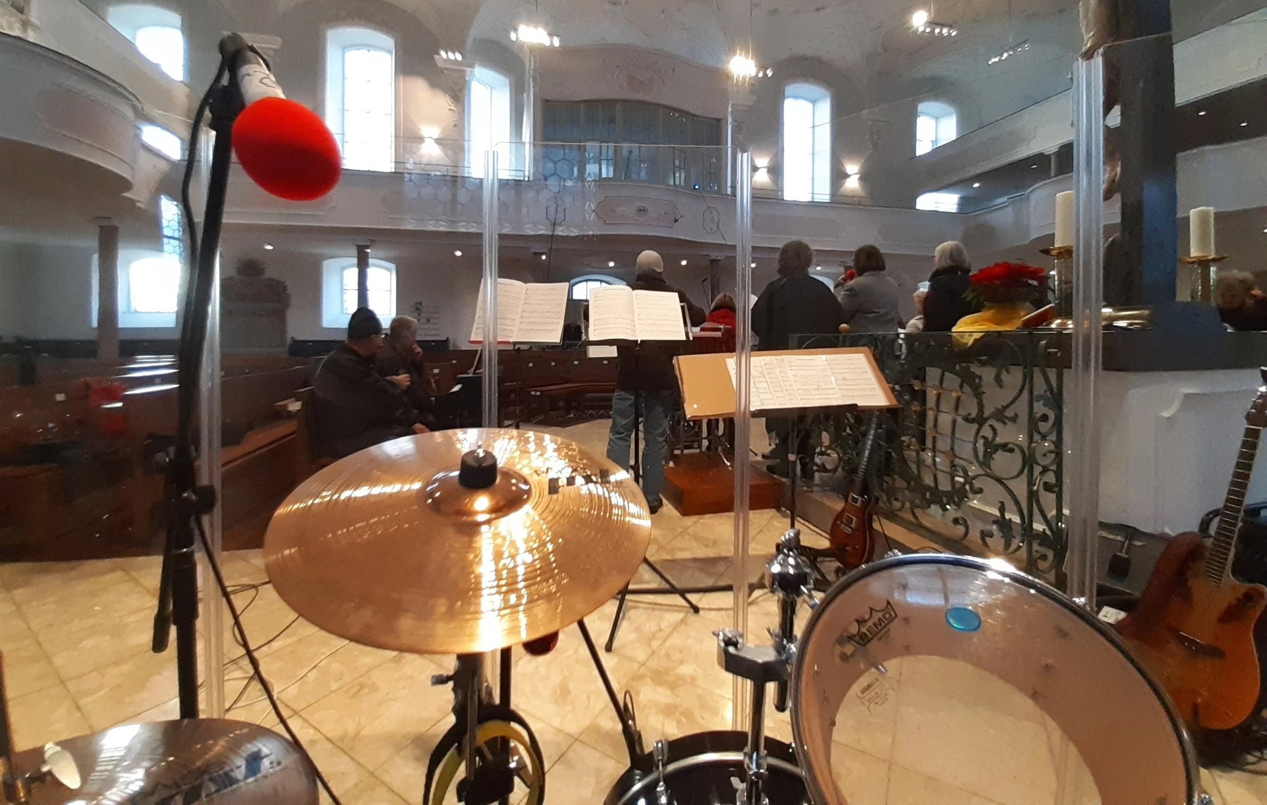 Blick in die Konzertkirche, mit mehreren Personen, einem Notenblatt, einem Gitarre und einem Schlagzeug, von der Bühne aus fotografiert.