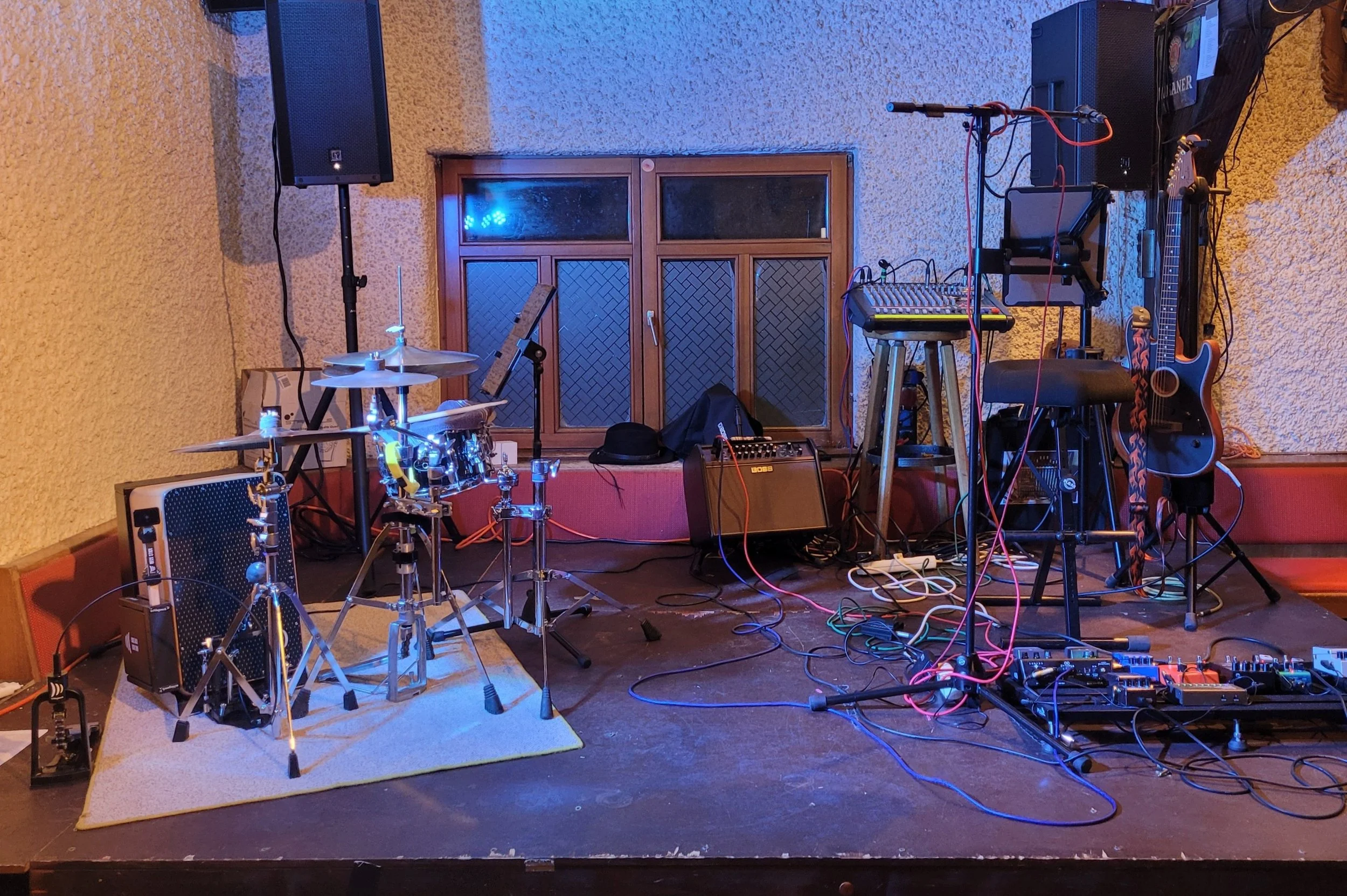 Bühne mit Musikinstrumenten, Lautsprechern und technischem Equipment für eine Live-Musik-Performance.