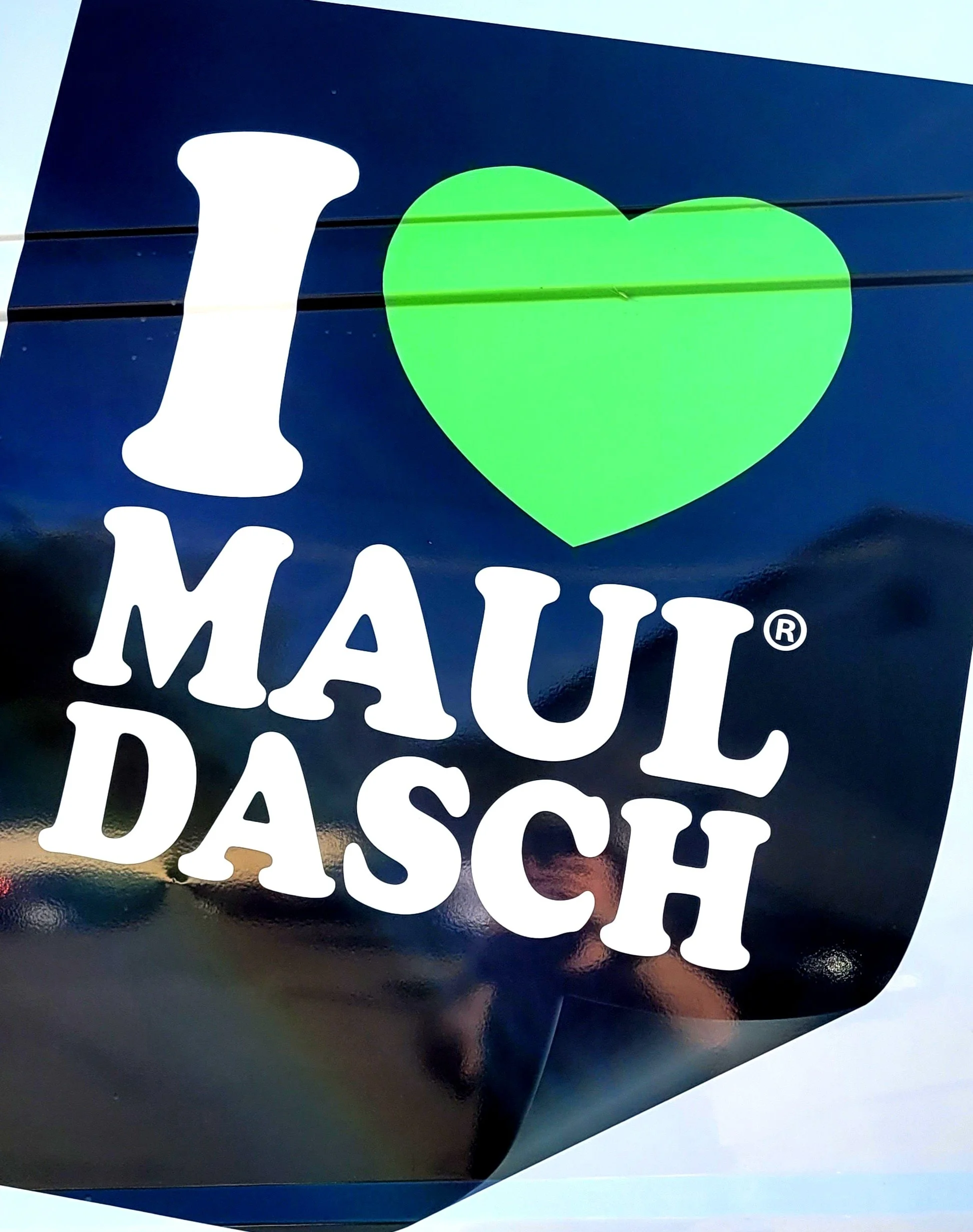 Ein Aufkleber mit der Aufschrift "I ♥ Mauldasch" auf einer schwarzen Oberfläche.