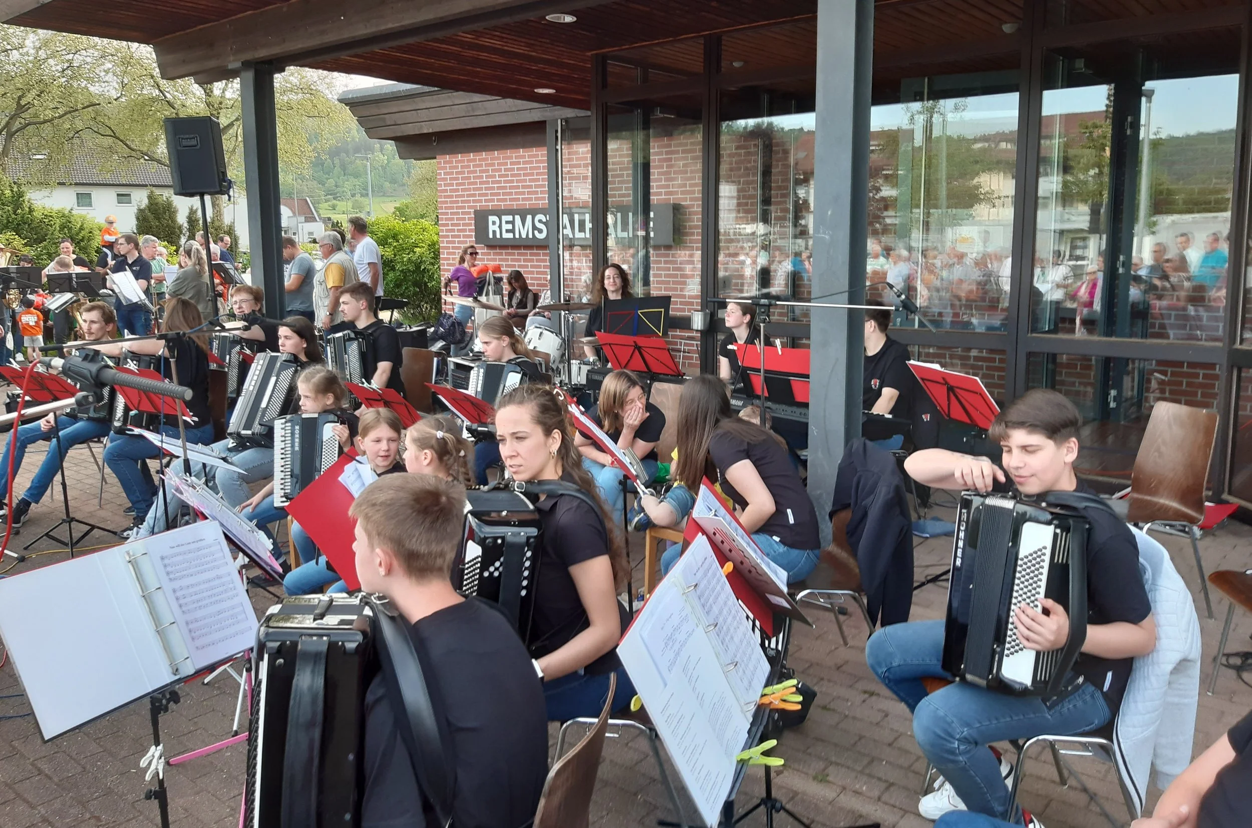 Jugendorchester mit jungen Musikern, die Notenblätter und Instrumente spielen, im Freien bei einem Konzert in Remshalden.