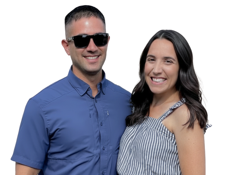 A smiling man with short dark hair, wearing sunglasses and a blue button-up shirt, standing next to a smiling woman with long dark hair, wearing a sleeveless striped top.