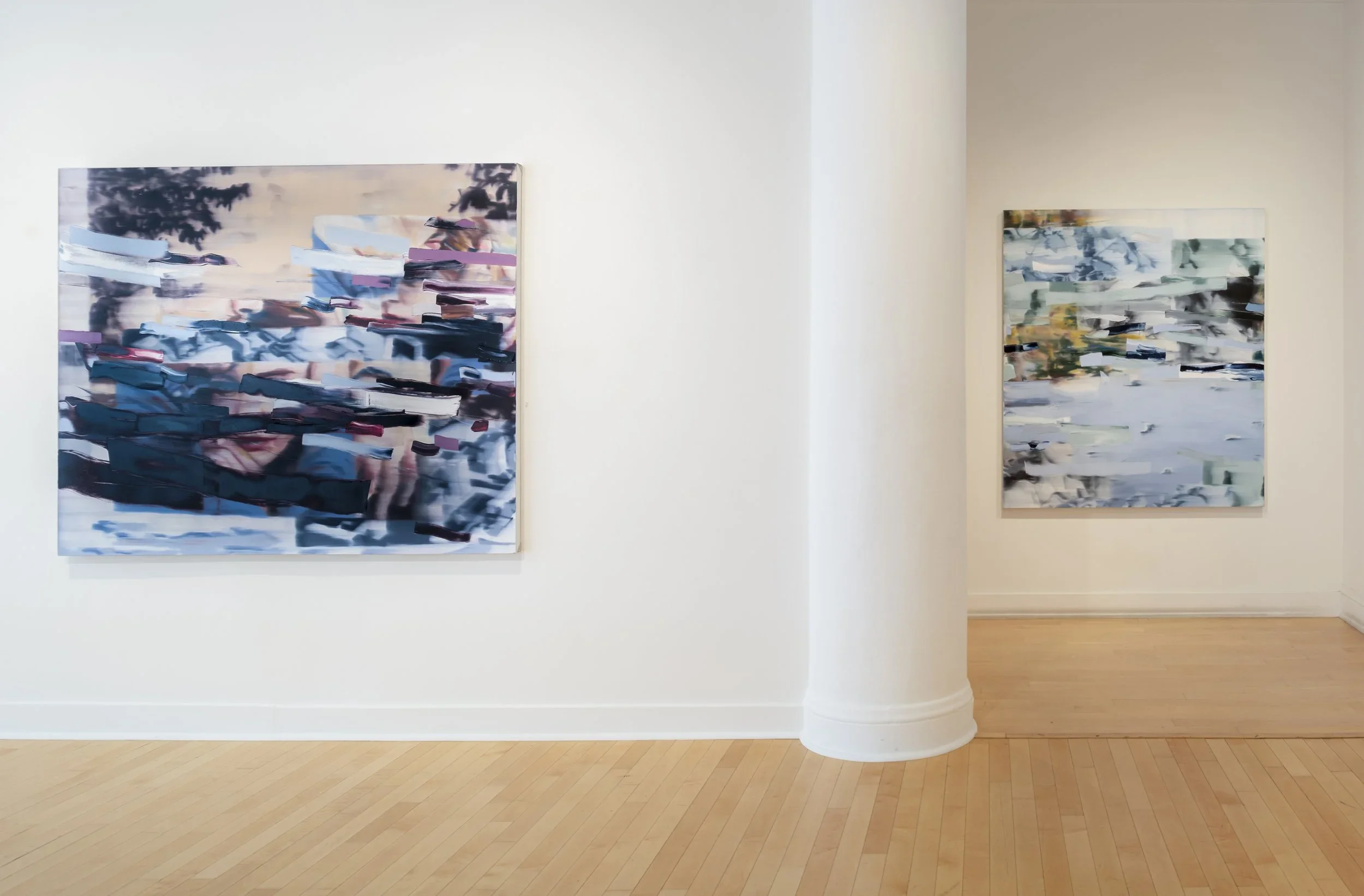 Two abstract paintings on a white gallery wall with light-colored hardwood floors.