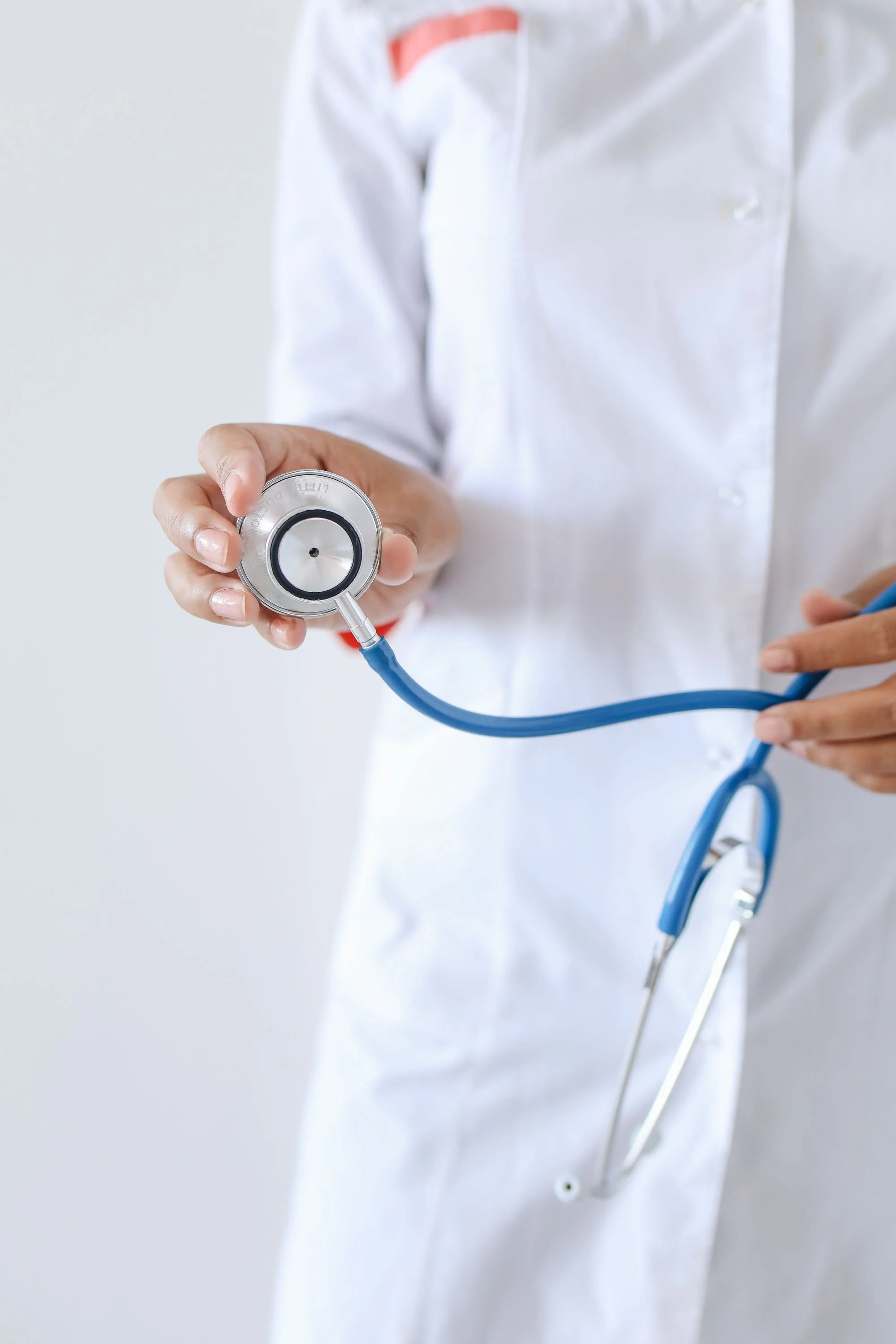 Close-up of a healthcare professional in a white coat holding a stethoscope.