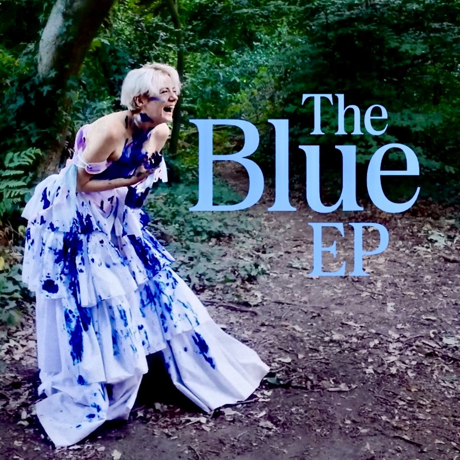 Rhys is in a forest, laughing. The text says “The Blue EP”