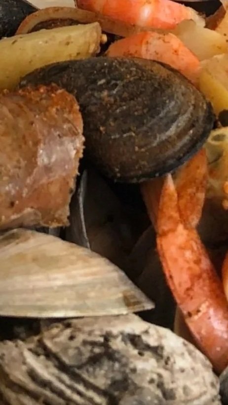 Grilled shellfish from Chef David Karlin, including mussels, clams, and possibly oysters, with grilled vegetables like carrots and zucchini.