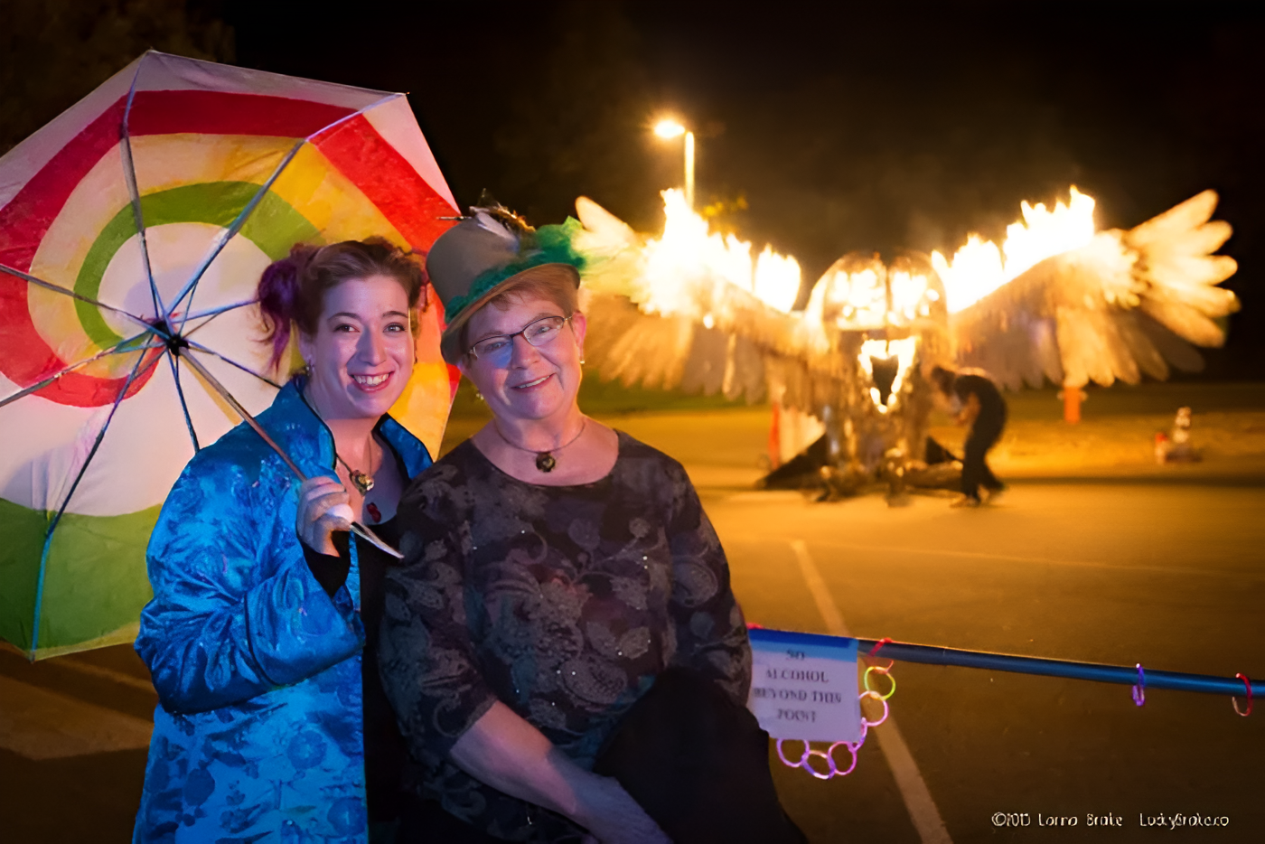 Two women standing in front of a lit owl sculpture