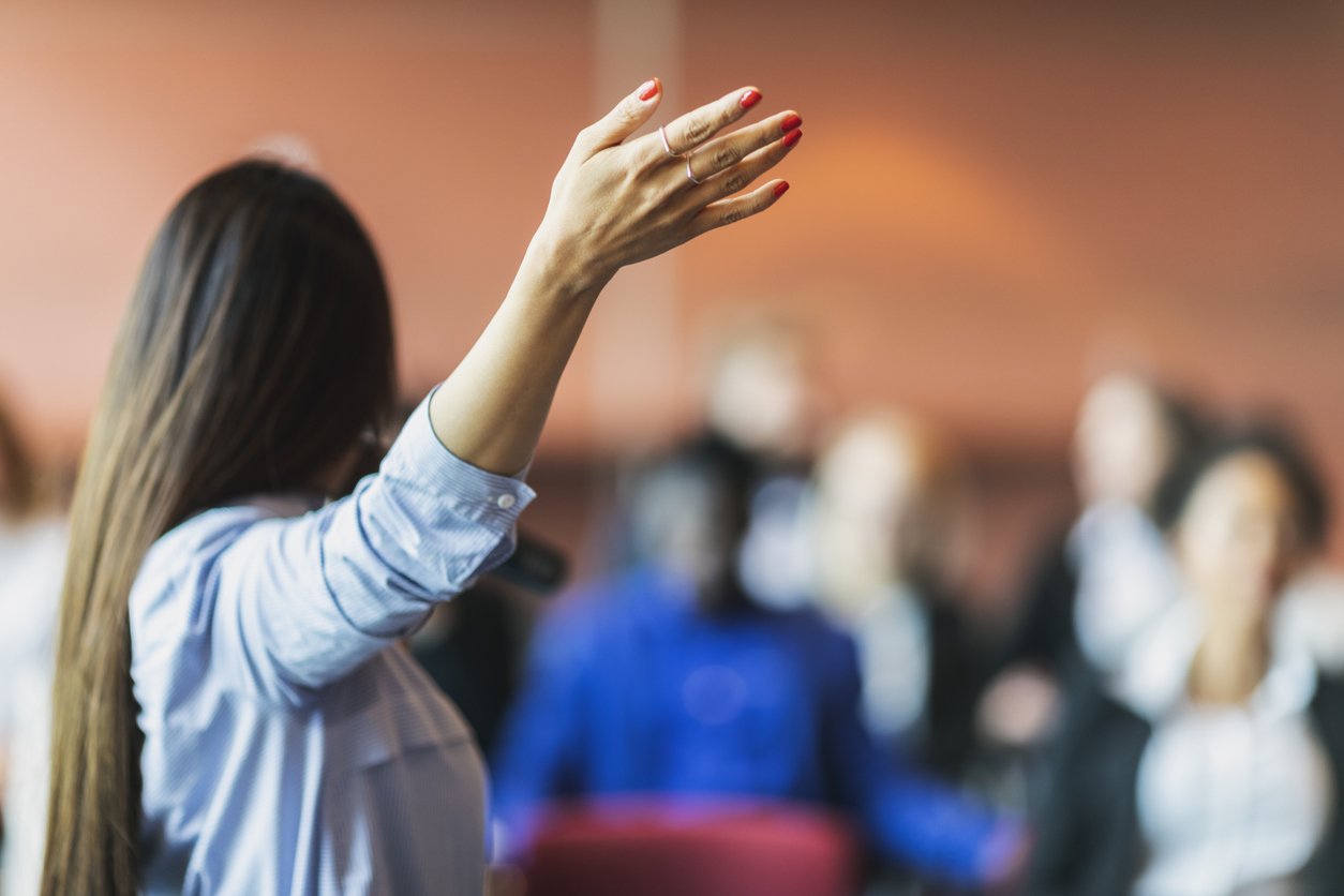 Back view of a woman speaking to a crowd