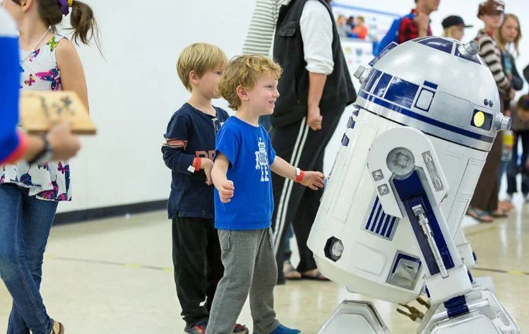 Two children boys standing next to a robot
