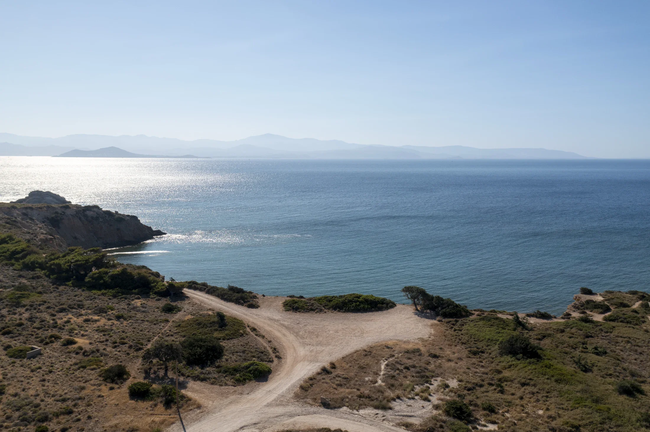 A coastal landscape with a trail leading down towards Skalakia beach in Paros, Cyclades island.