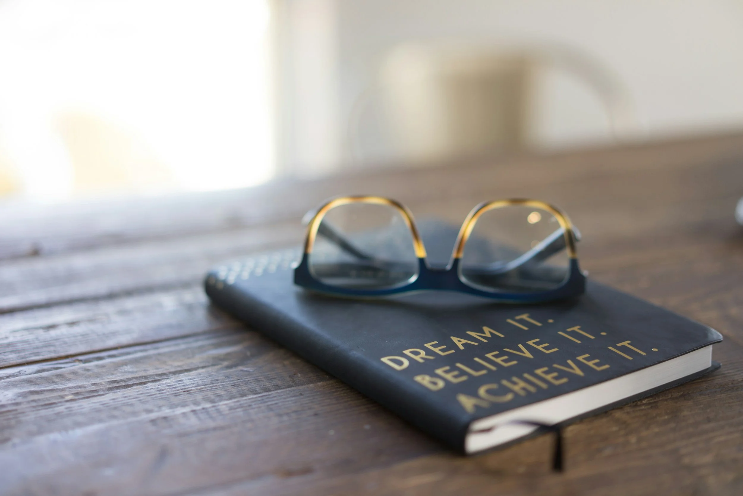 Notebook with "Dream It, Believe It, Achieve It" quote representing the growth mindset behind Maverick HQ's marketing approach.