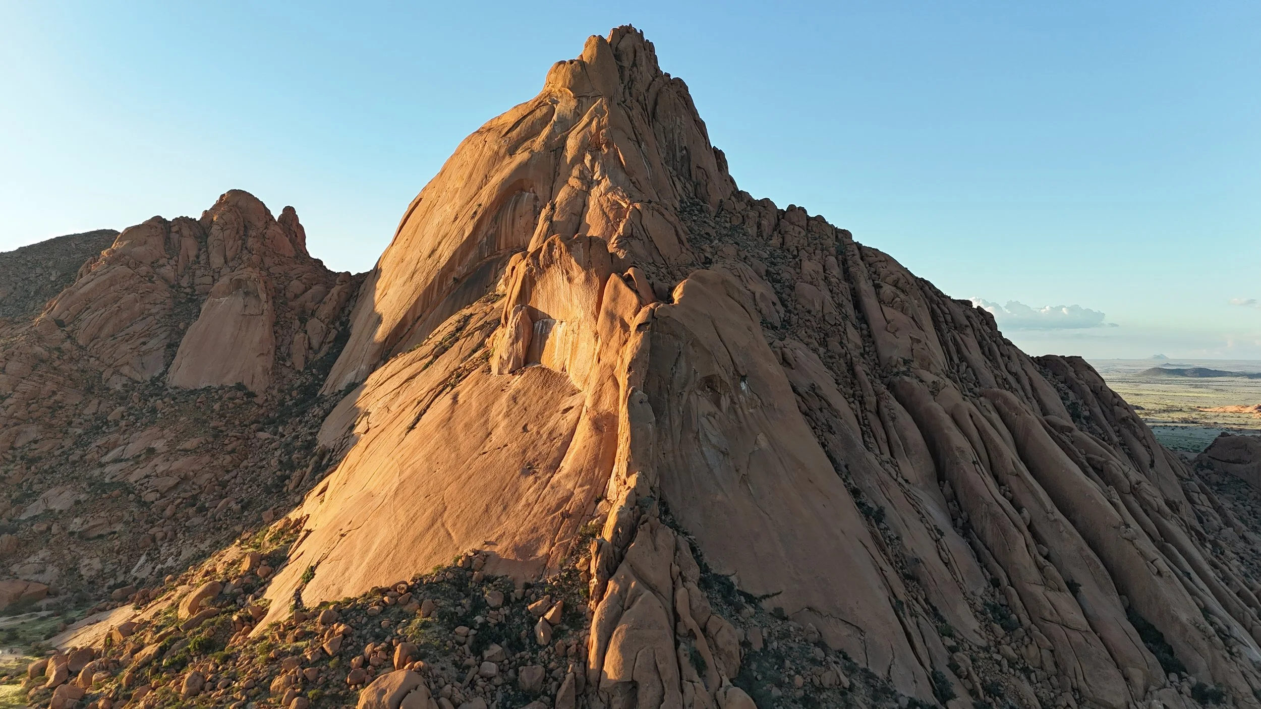A large rocky mountain with steep, rugged slopes under a clear sky.
