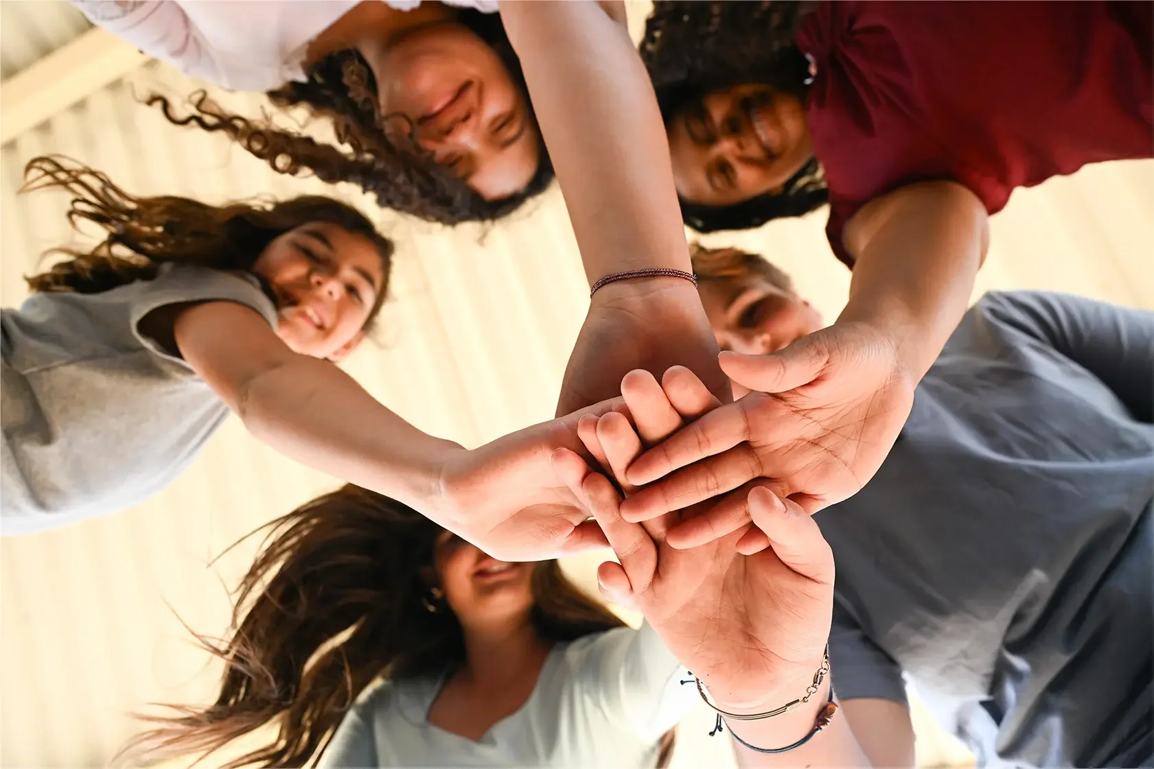 Group of diverse people participating in a team huddle, placing their hands together in the center.
