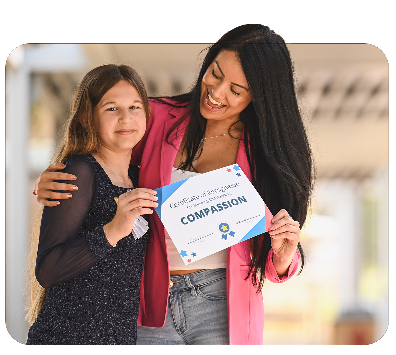 A woman and a girl holding a certificate of recognition for showing compassion, smiling and standing close together.