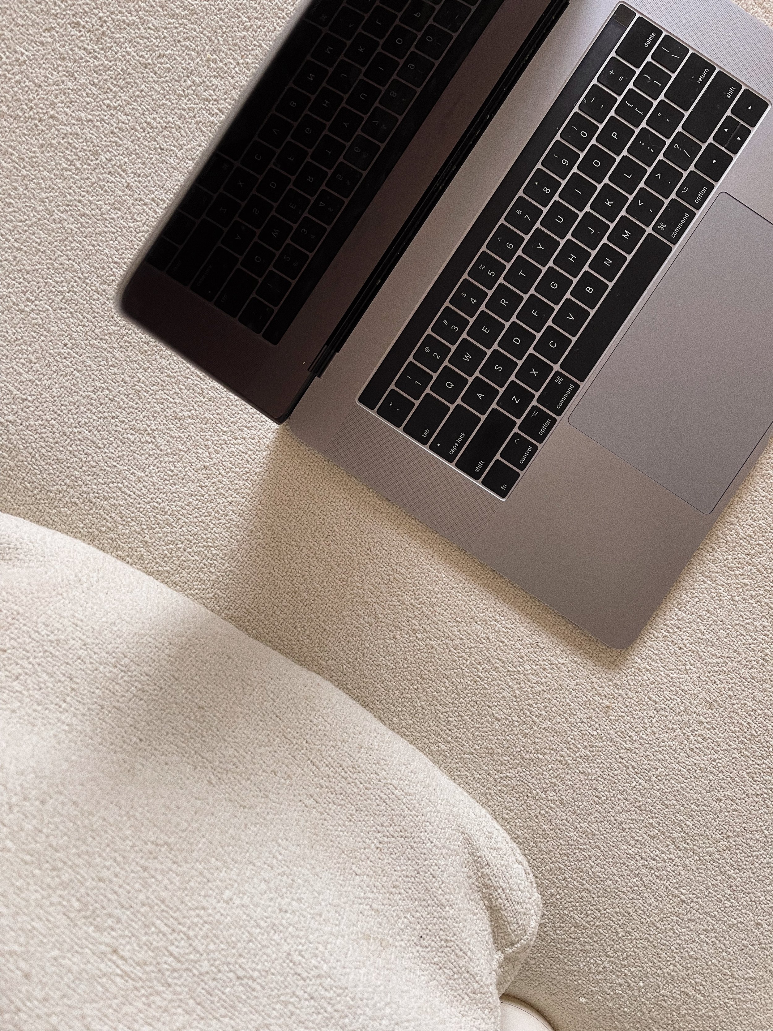 Close-up of a silver laptop with black keyboard, resting on a textured, beige fabric surface.