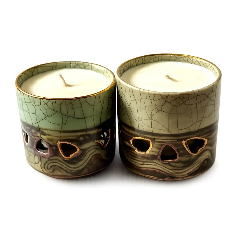 Two ceramic candles with skull-shaped cutouts and crackled glaze design.