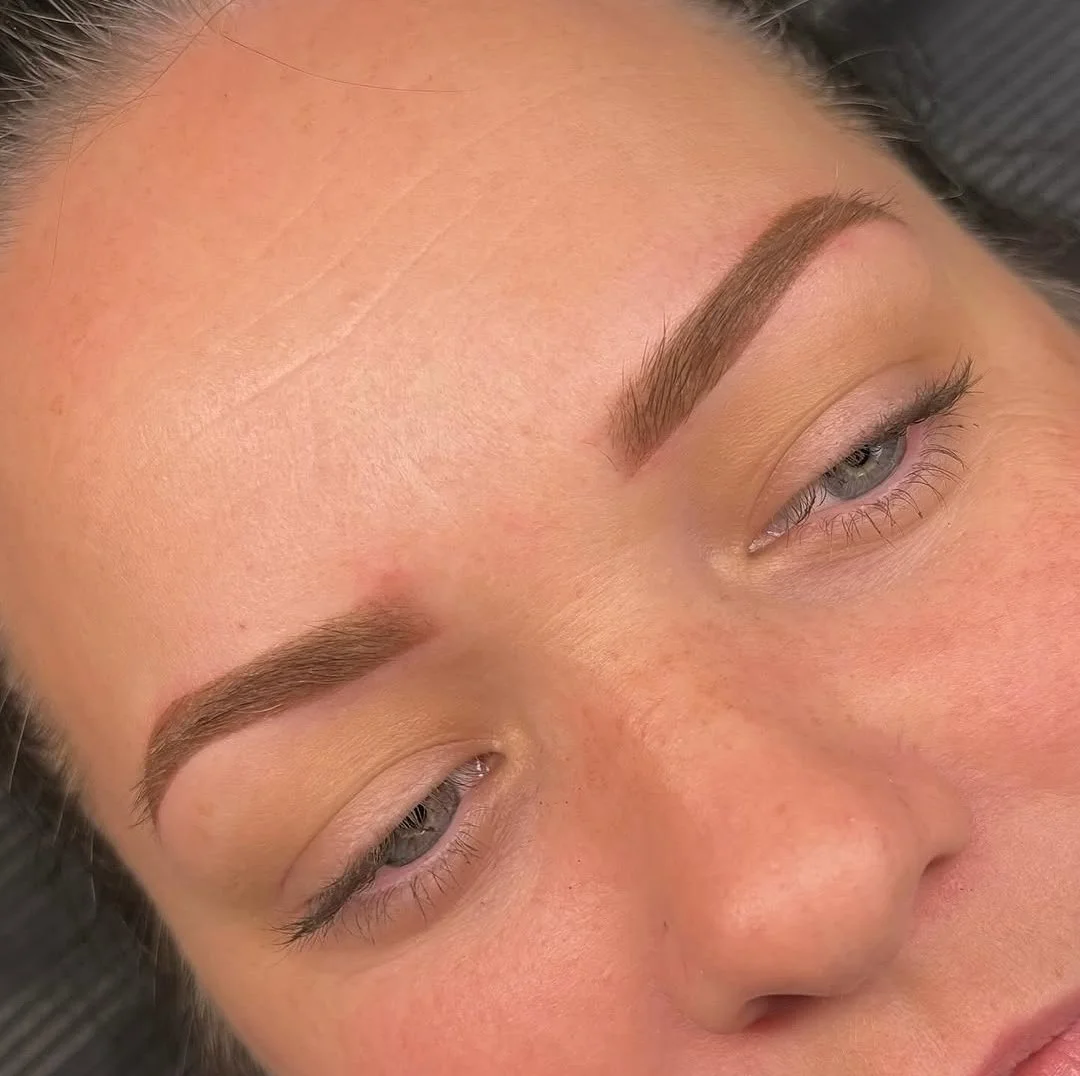 Close-up of a woman's face focusing on her well-groomed eyebrows and partly closed eyes.