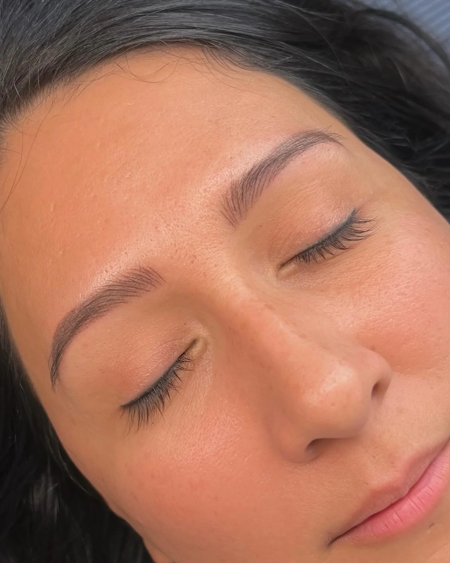 Close-up of a woman's face with her eyes closed, showing well-groomed eyebrows and smooth skin.