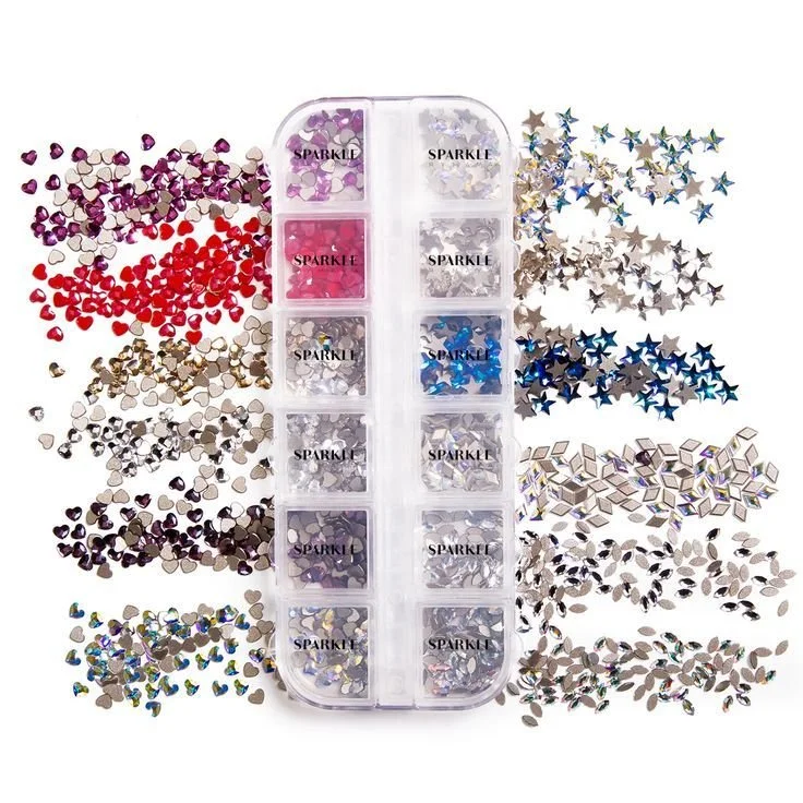 Container of ten compartments with various shaped and colored glitter and rhinestones, surrounded by scattered star-shaped glitter and small decorative stones.