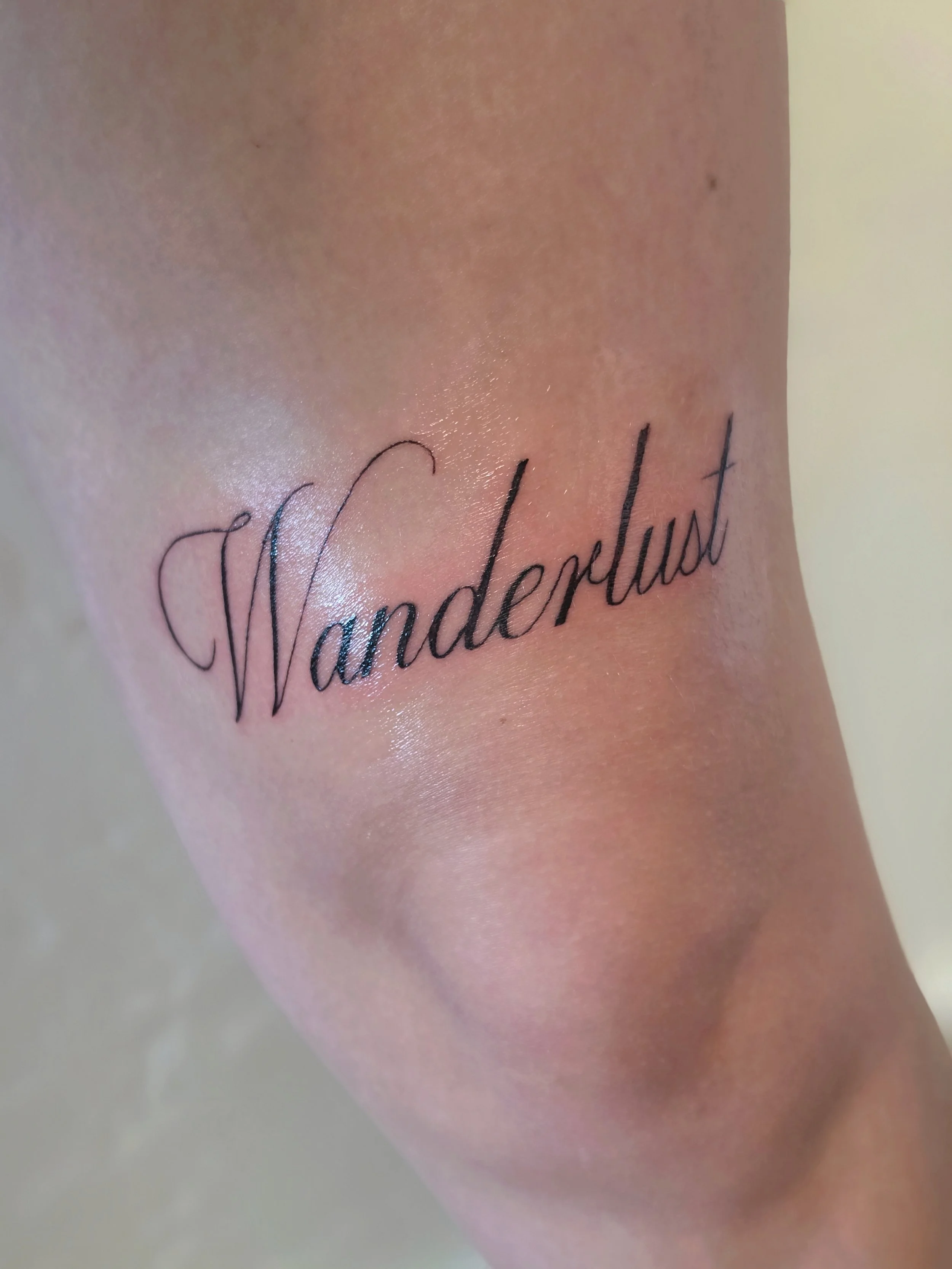 Close-up of a person's skin tattoo that reads 'Tenderheart' in elegant cursive font.