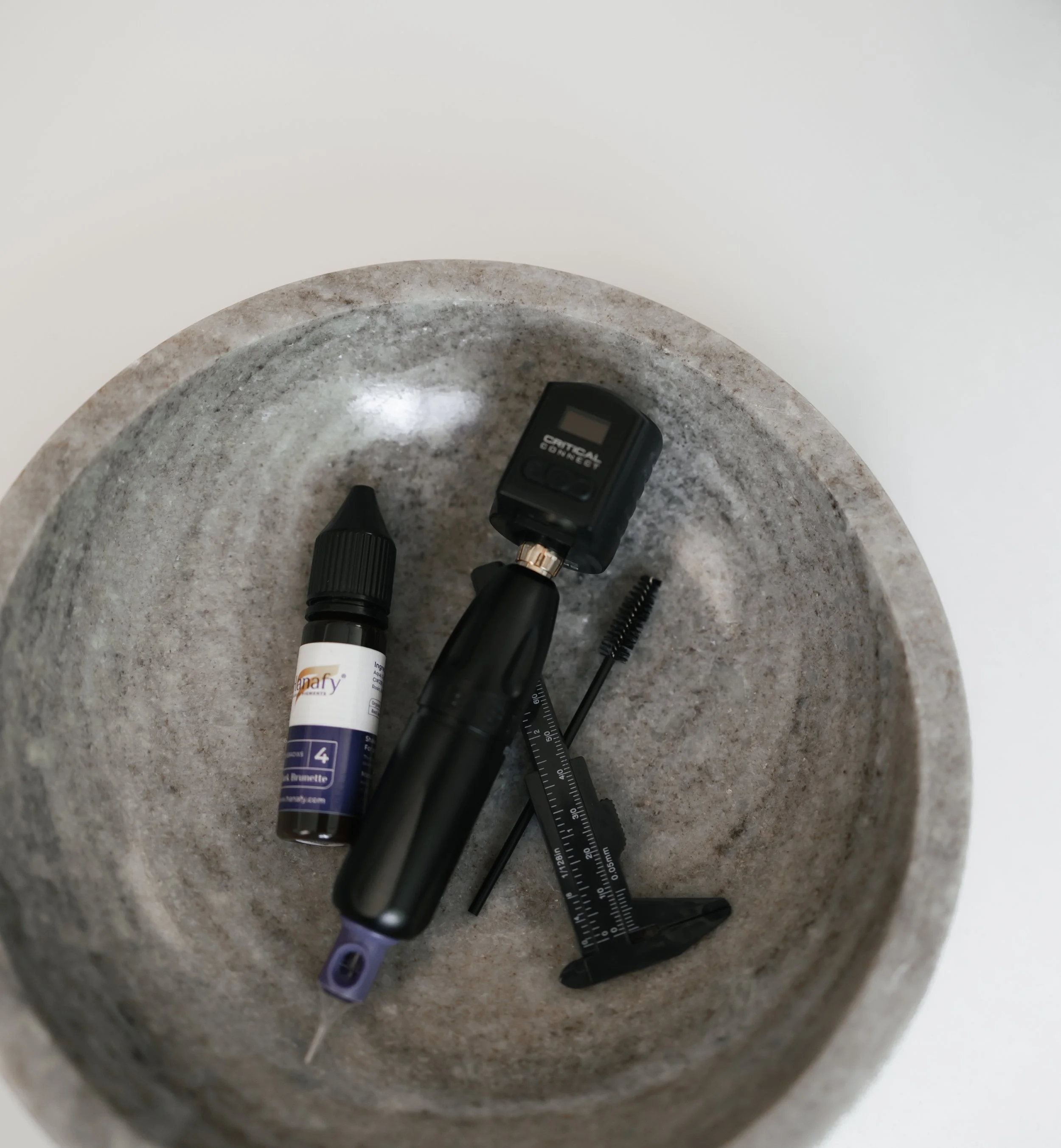 A medical syringe, a black blood lancet device, and a small black measuring device are placed on a circular gray stone surface.