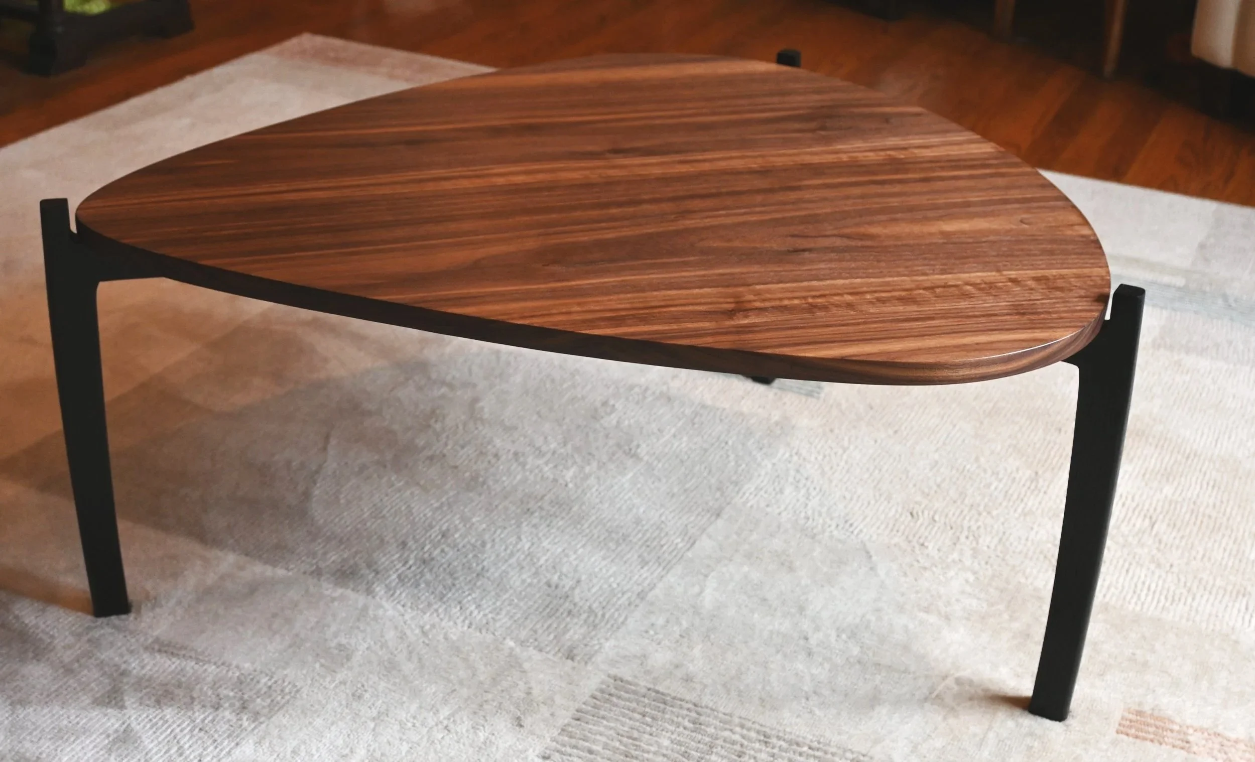 Walnut guitar-pick shaped table with oak legs ebonized to a dark black.