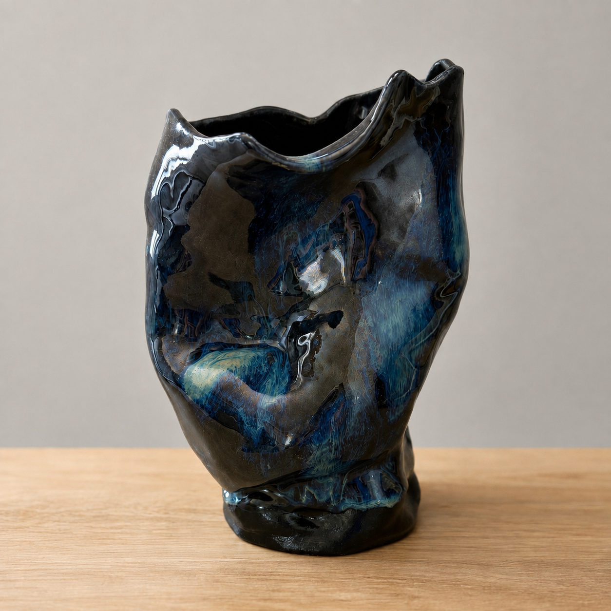 Handcrafted blue and black sculptural ceramic vase displayed on a wooden surface.