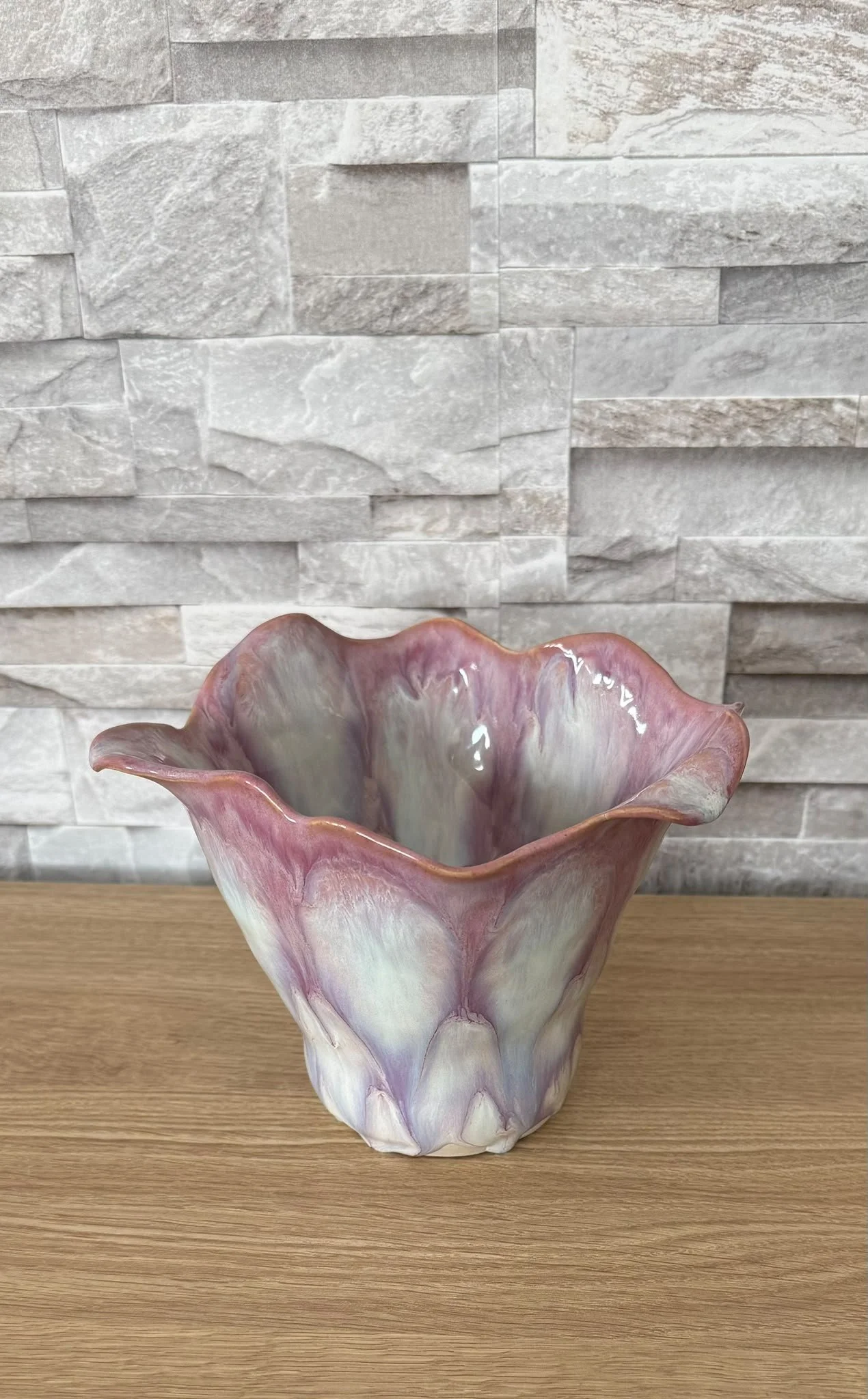 Blush pink sculptural ceramic vase with a flowing, ruffled rim and organic form.
