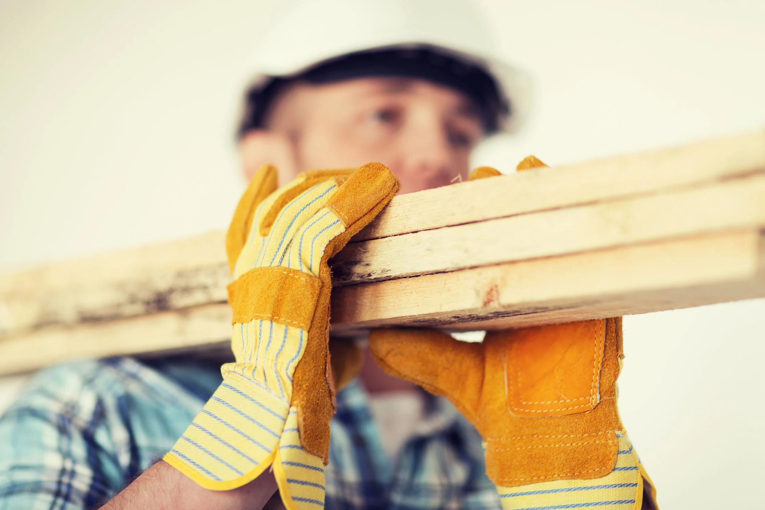 Une personne portant des gants de travaux maintient une planche en bois.