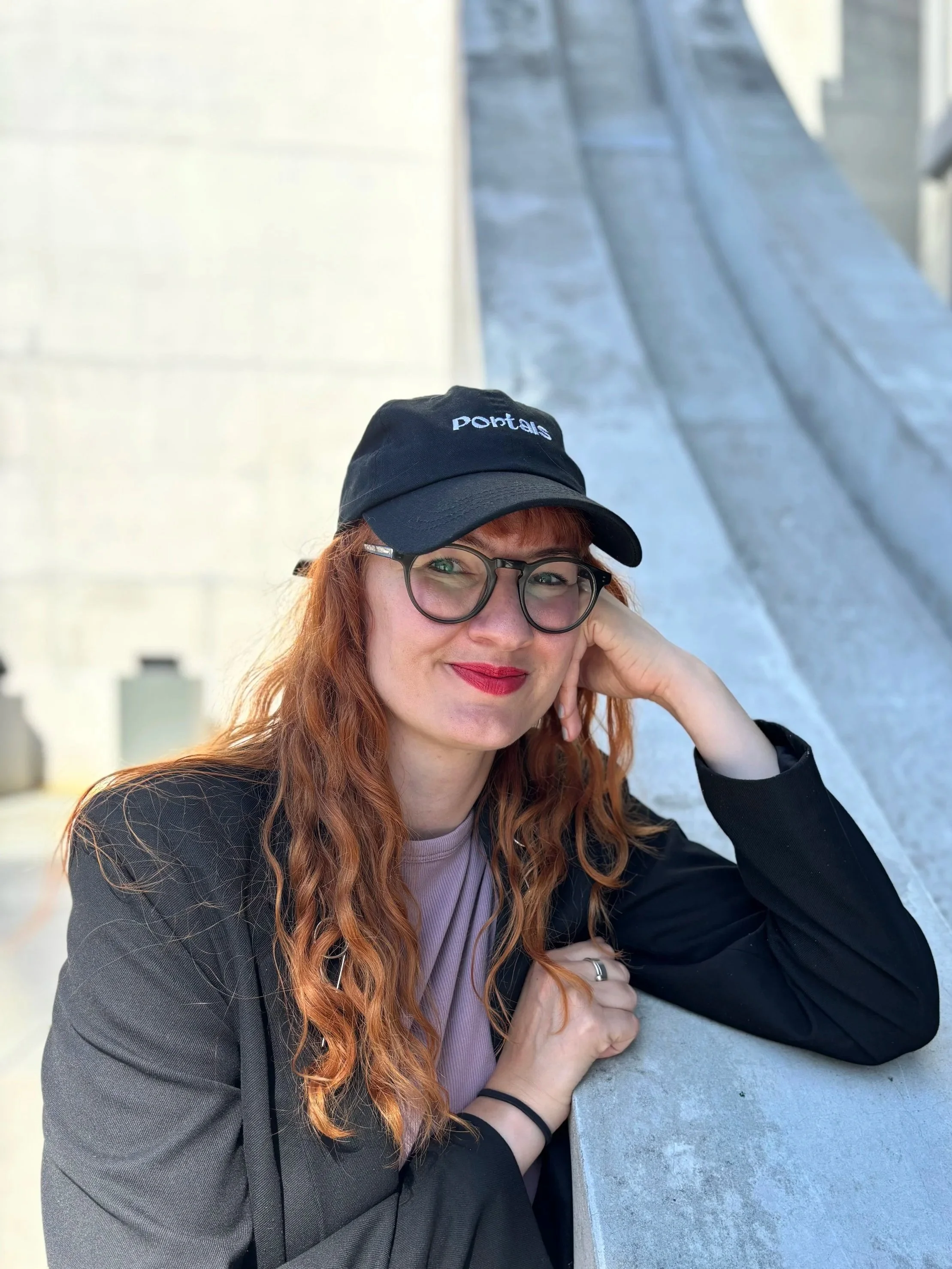 Kat Thiel of Portals Hypnotherapy, wearing a black Portals cap, on the contact page.