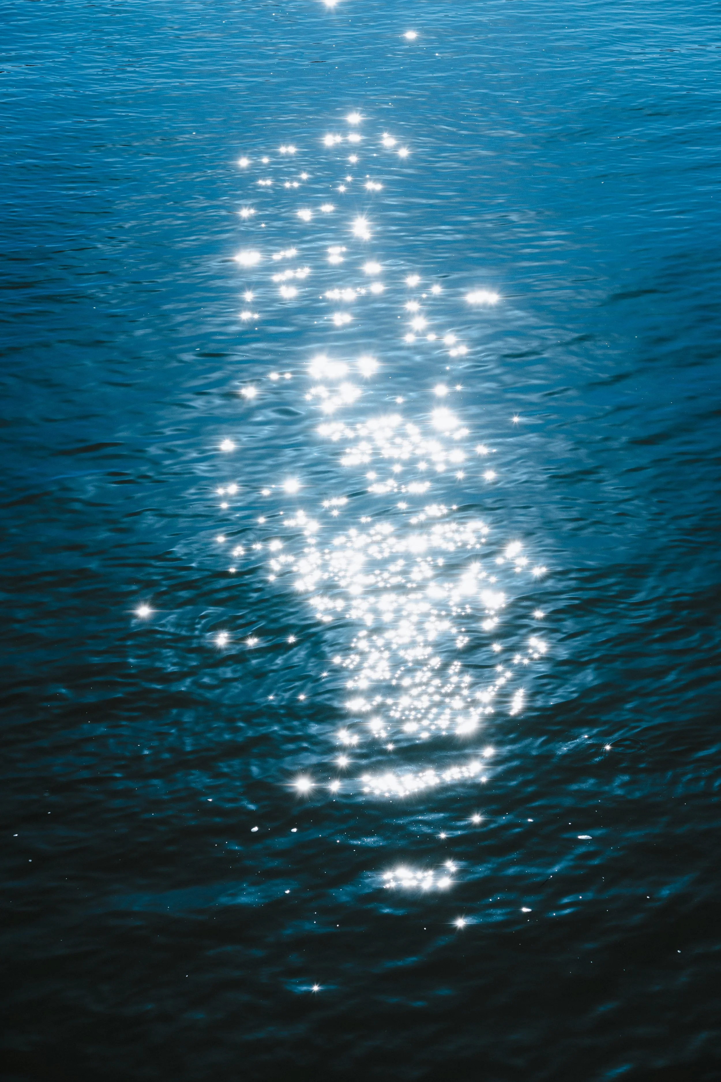 Sunlight reflections on a calm blue water surface.