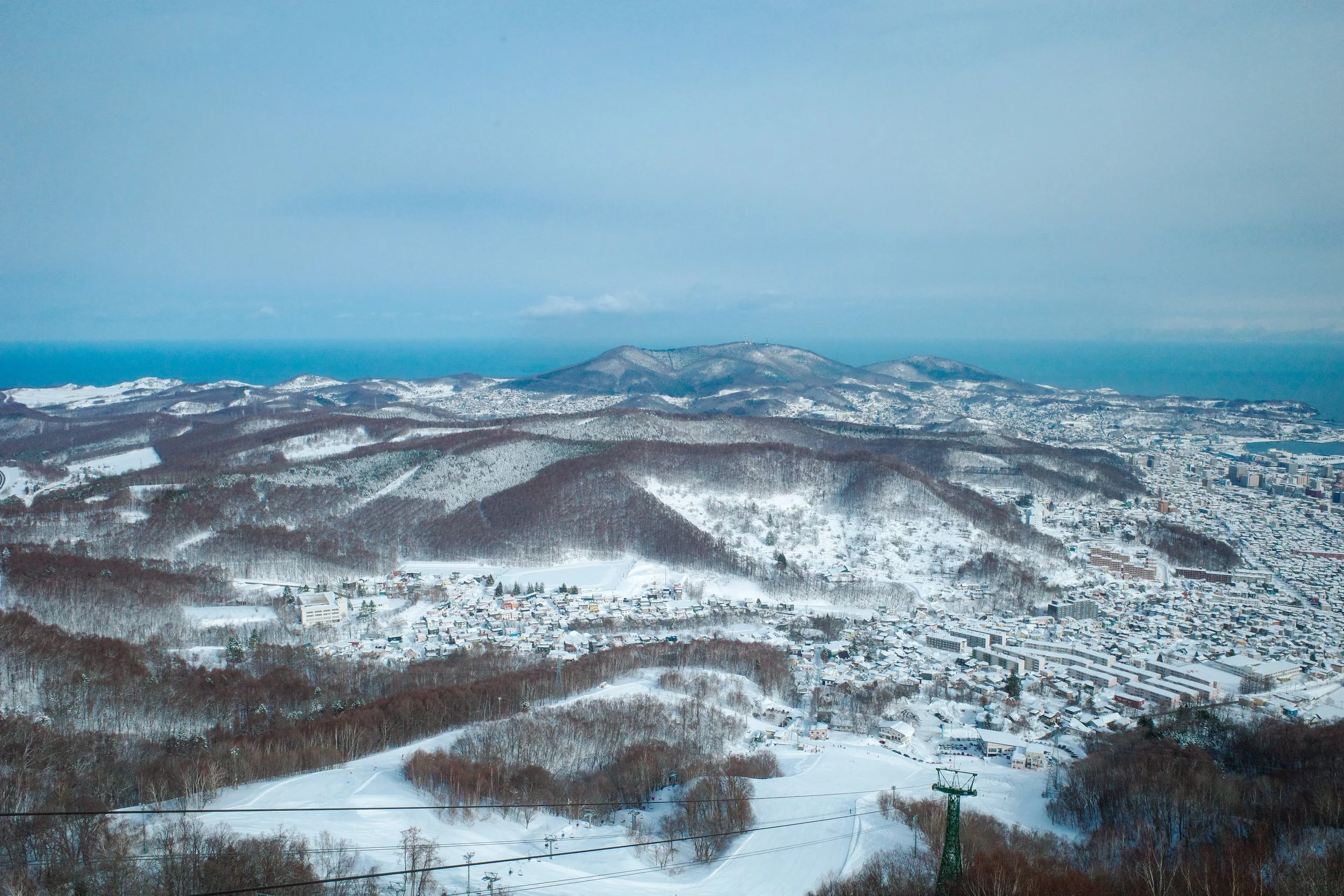 Snow-covered mountains and a small town at their base, with ski lifts and ski slopes visible in the foreground.