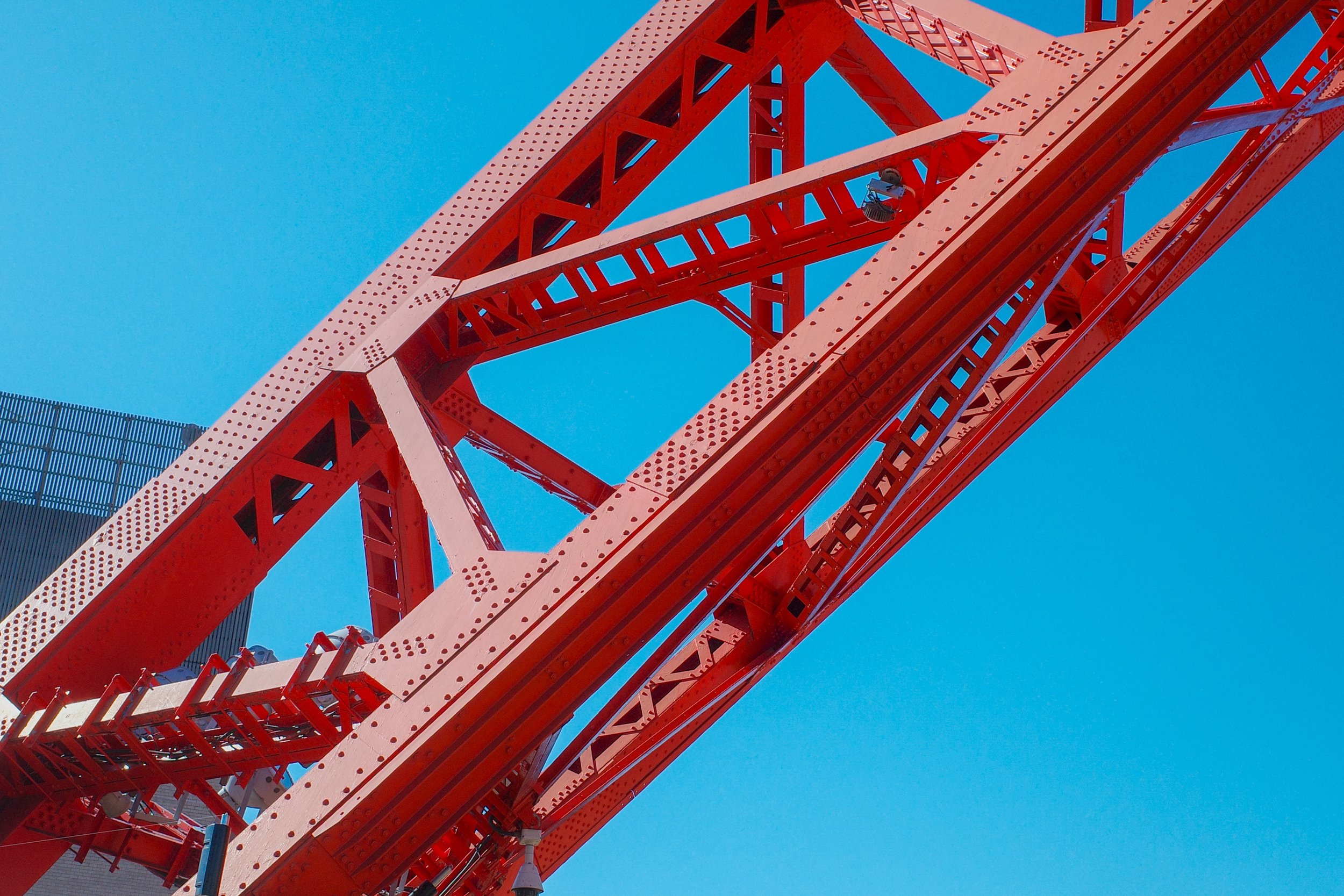 Close-up view of a red Ferris wheel structure against a clear blue sky.