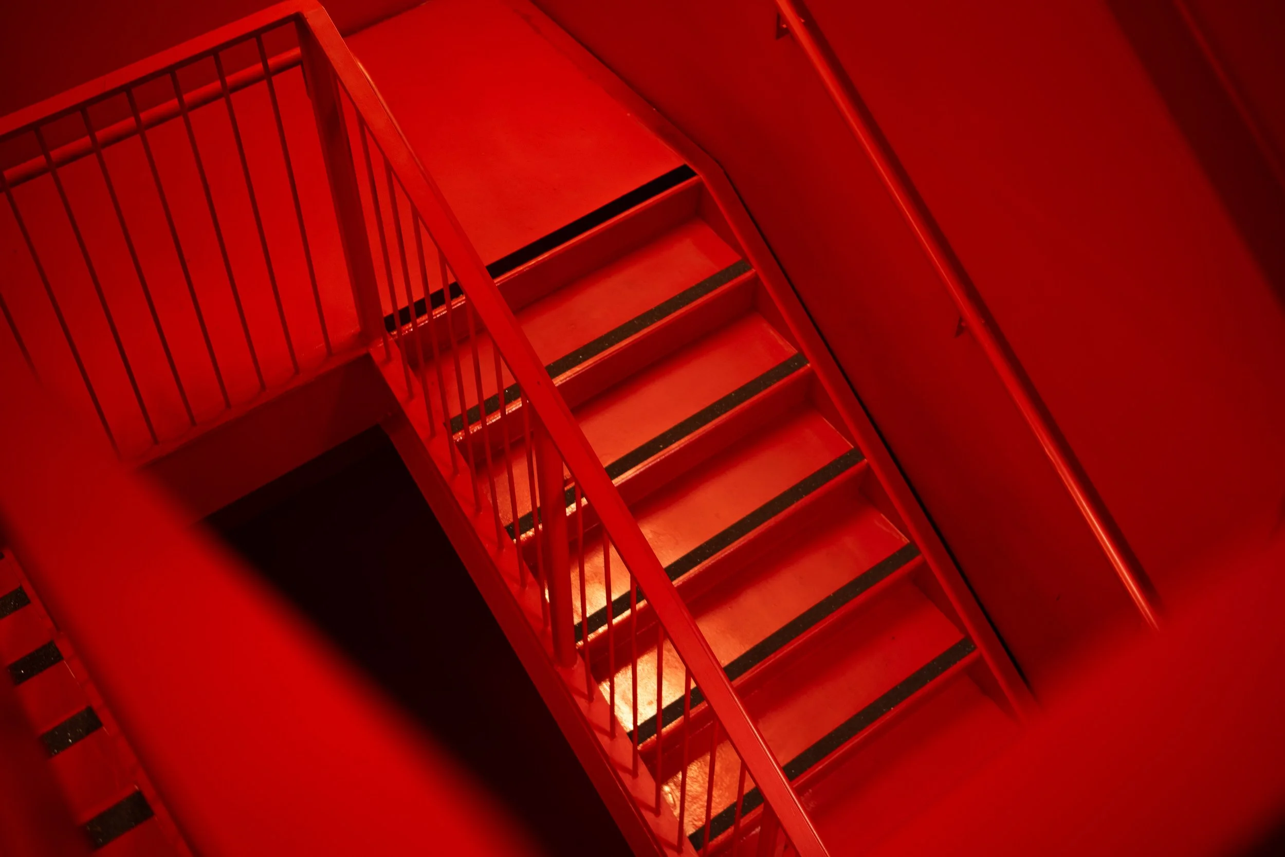 Red staircase with metal railings viewed from above.