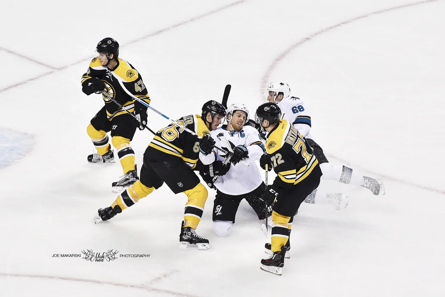 Hockey players engaged in a fight on the ice during a game, with players from both teams grabbing each other.