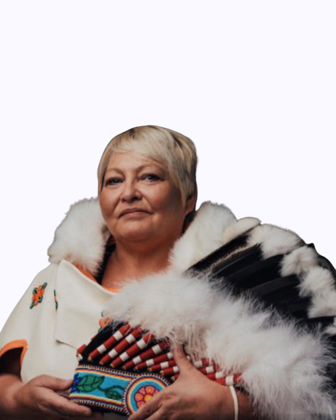 A woman with short blonde hair, wearing a Simba shawl, holding a colorful fabric bag, with a white background.