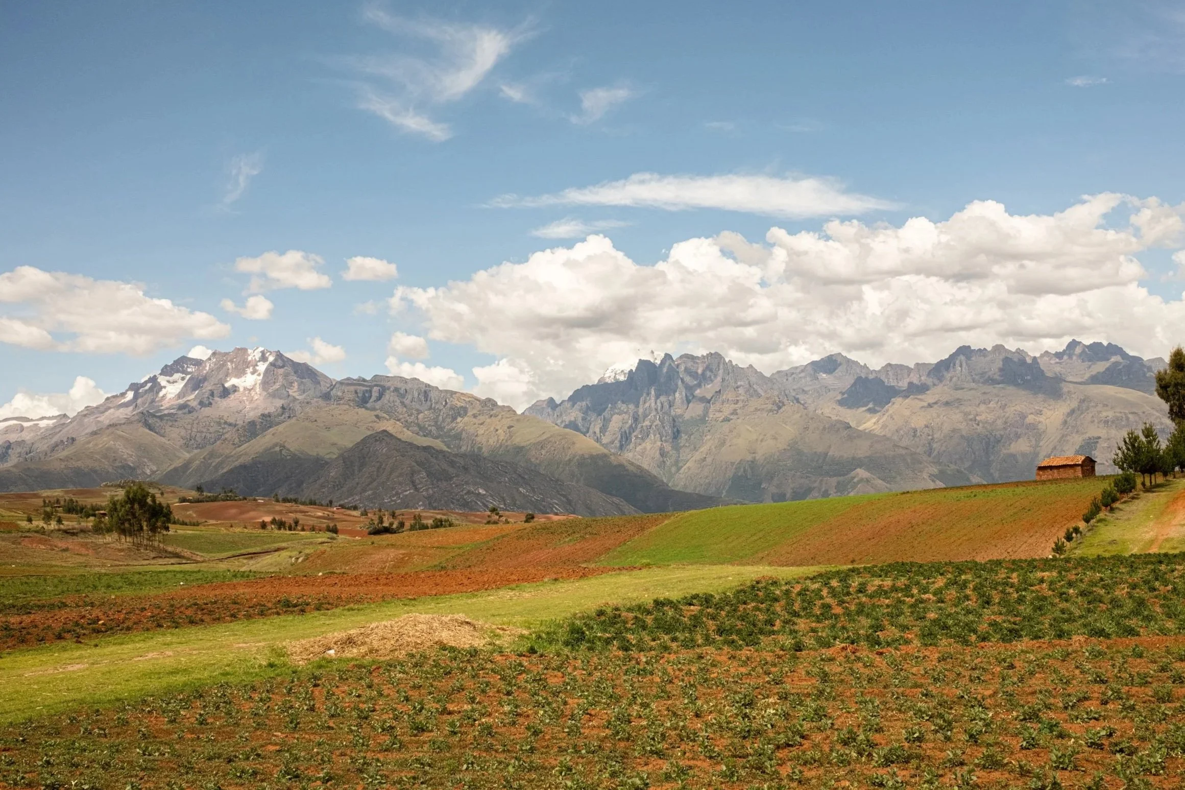 Rolling farmland and mountains under a cloudy sky