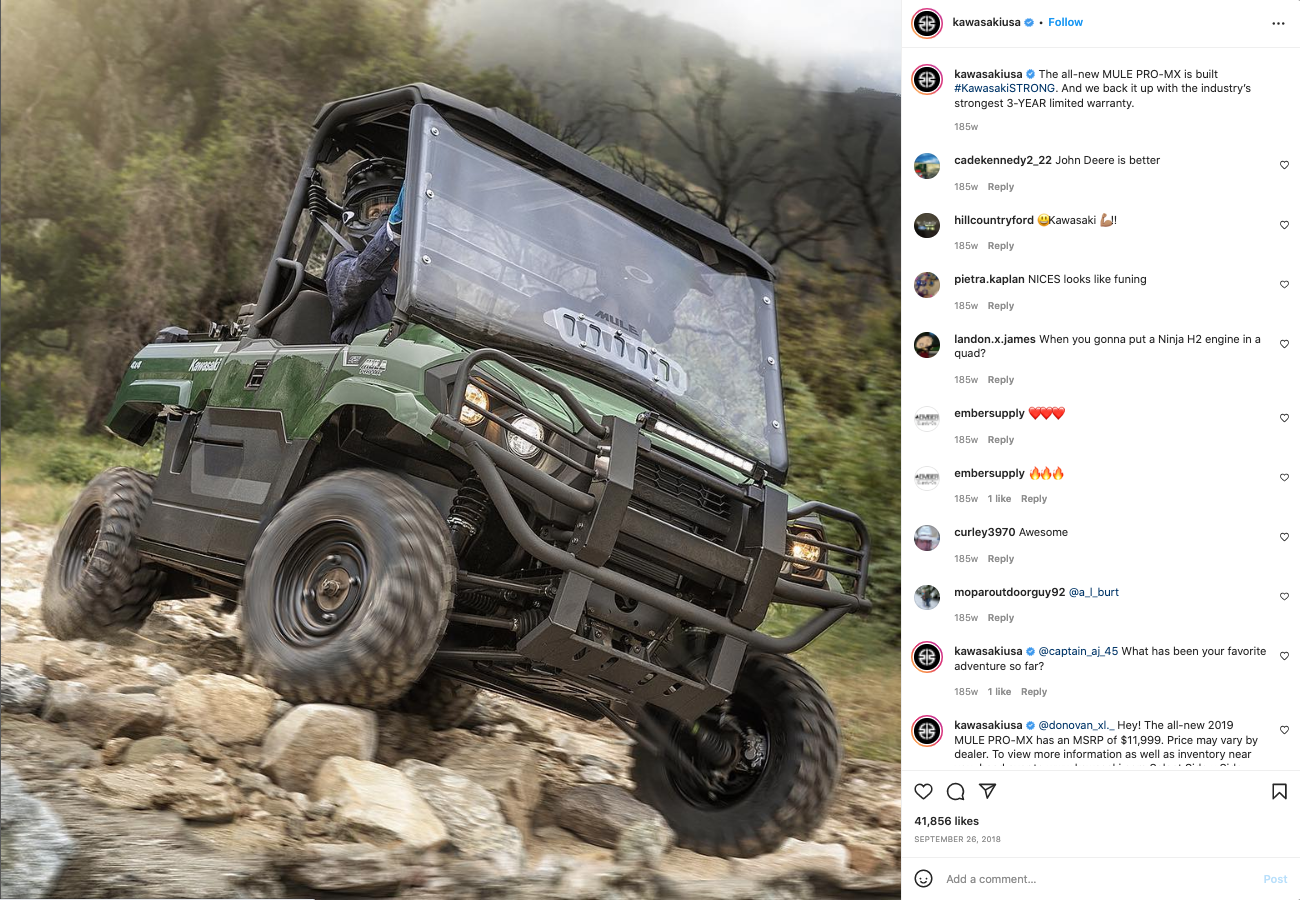 A green Kawasaki Mule off-road utility vehicle navigating over rocky terrain, with a rider wearing a helmet and blue gloves inside.