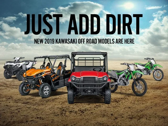 Off-road vehicles including a quad bike, a utility vehicle, a dirt bike, and a motocross bike on a dirt track with cloudy sky background. Text overlay says "Just Add Dirt" and "New 2019 Kawasaki Off Road Models Are Here."