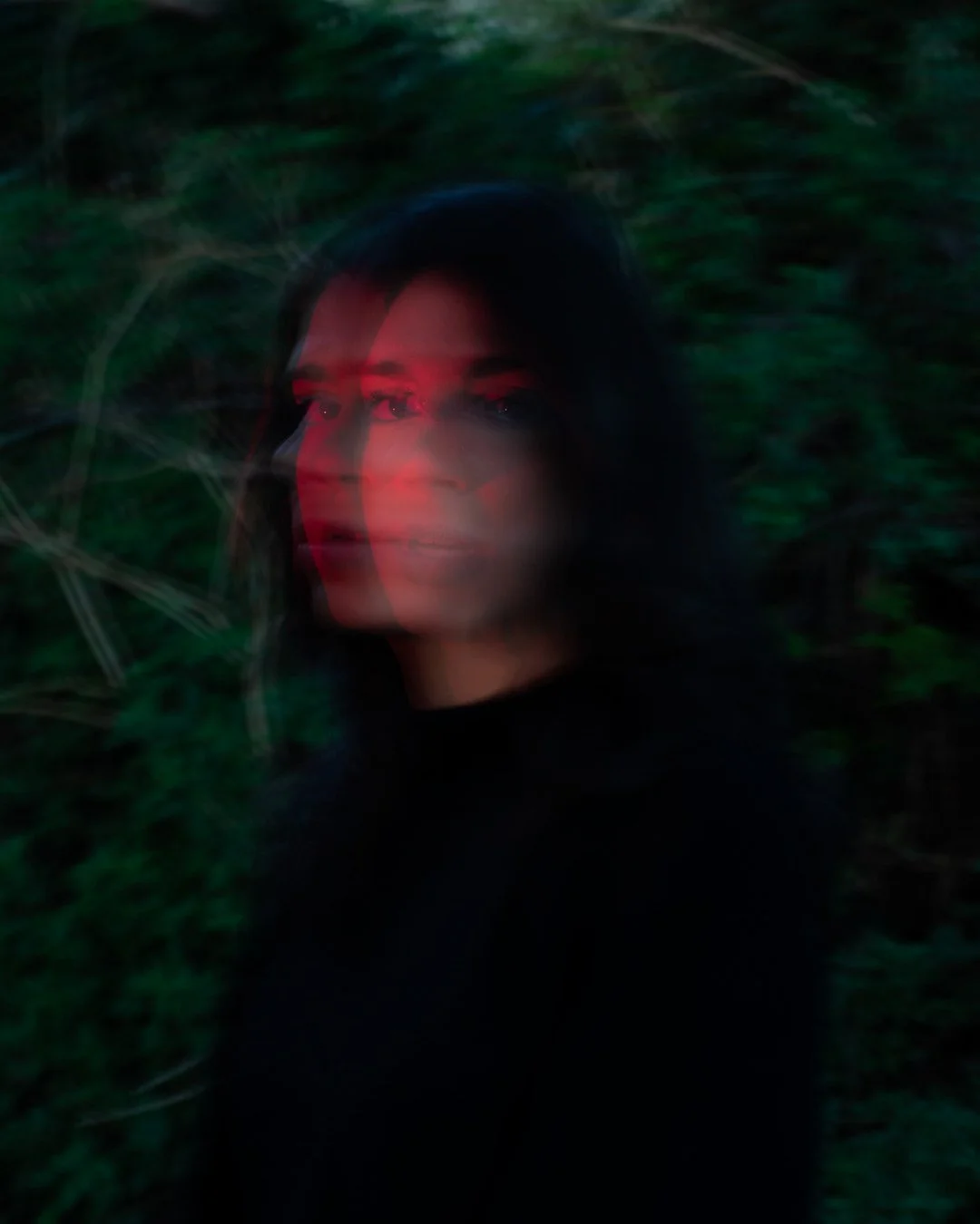 Ragazza con effetti di movimento e luce rossa in un ambiente naturale o bosco.