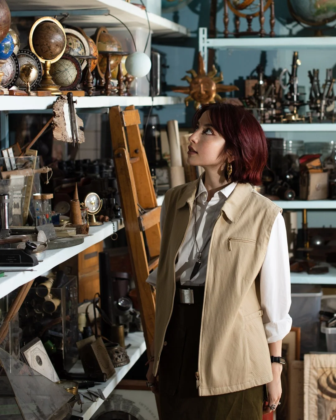 Una donna con i capelli rossi che osserva oggetti antichi e vintage sugli scaffali in un negozio di antiquariato o mercatino.
