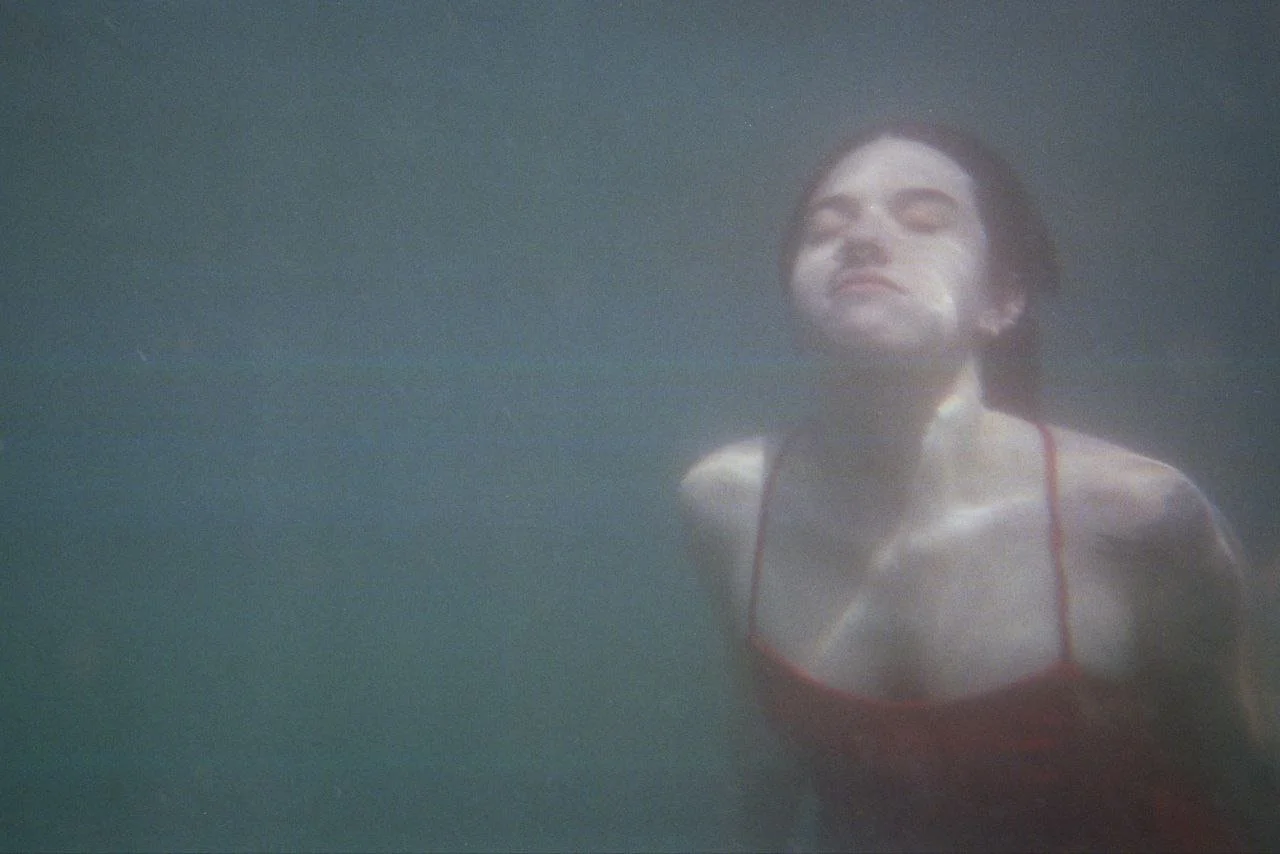 Donna che si tuffa sott'acqua con espressione serena in posa elegante.