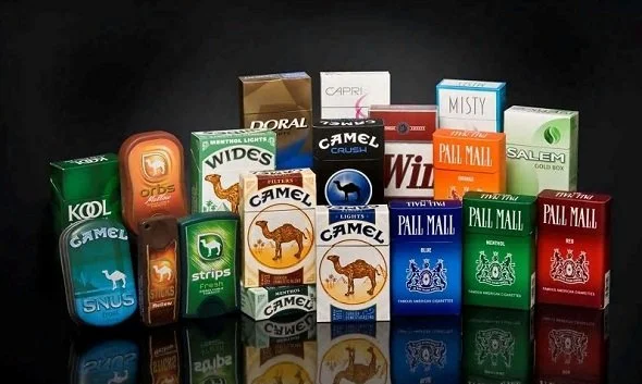A collection of various cigarette and tobacco product packs displayed on a black surface.