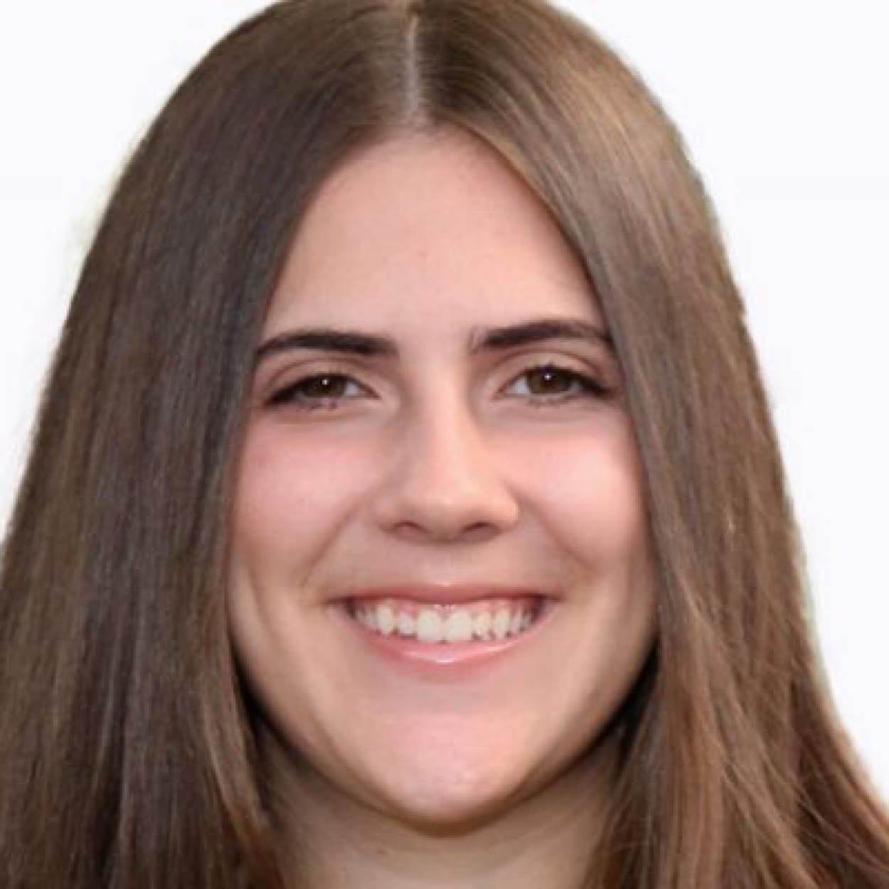 Close-up of a young woman with long brown hair, smiling, with light makeup, against a plain background.
