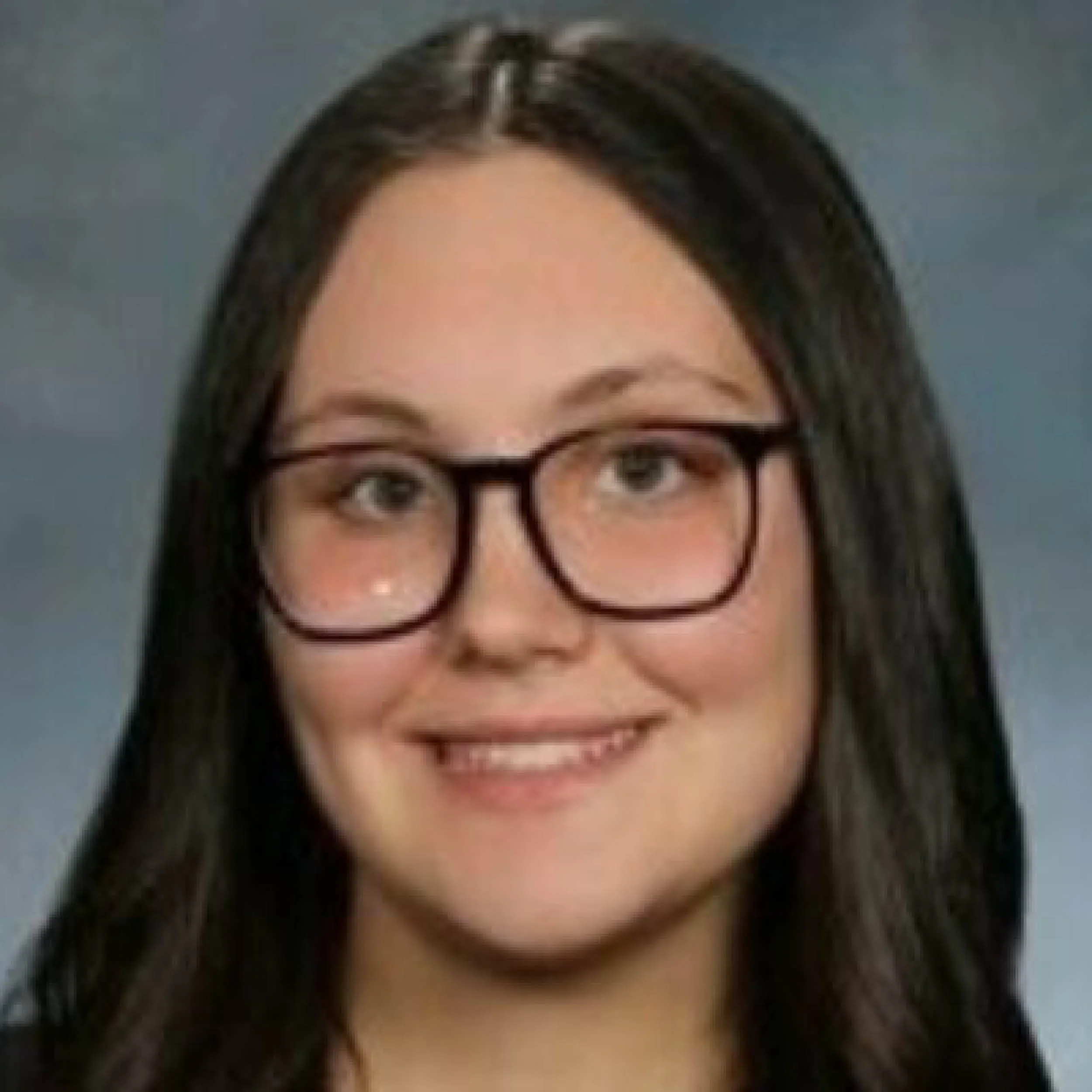 Woman with black hair, wearing glasses, smiling, and showing her eyes and eyebrows.