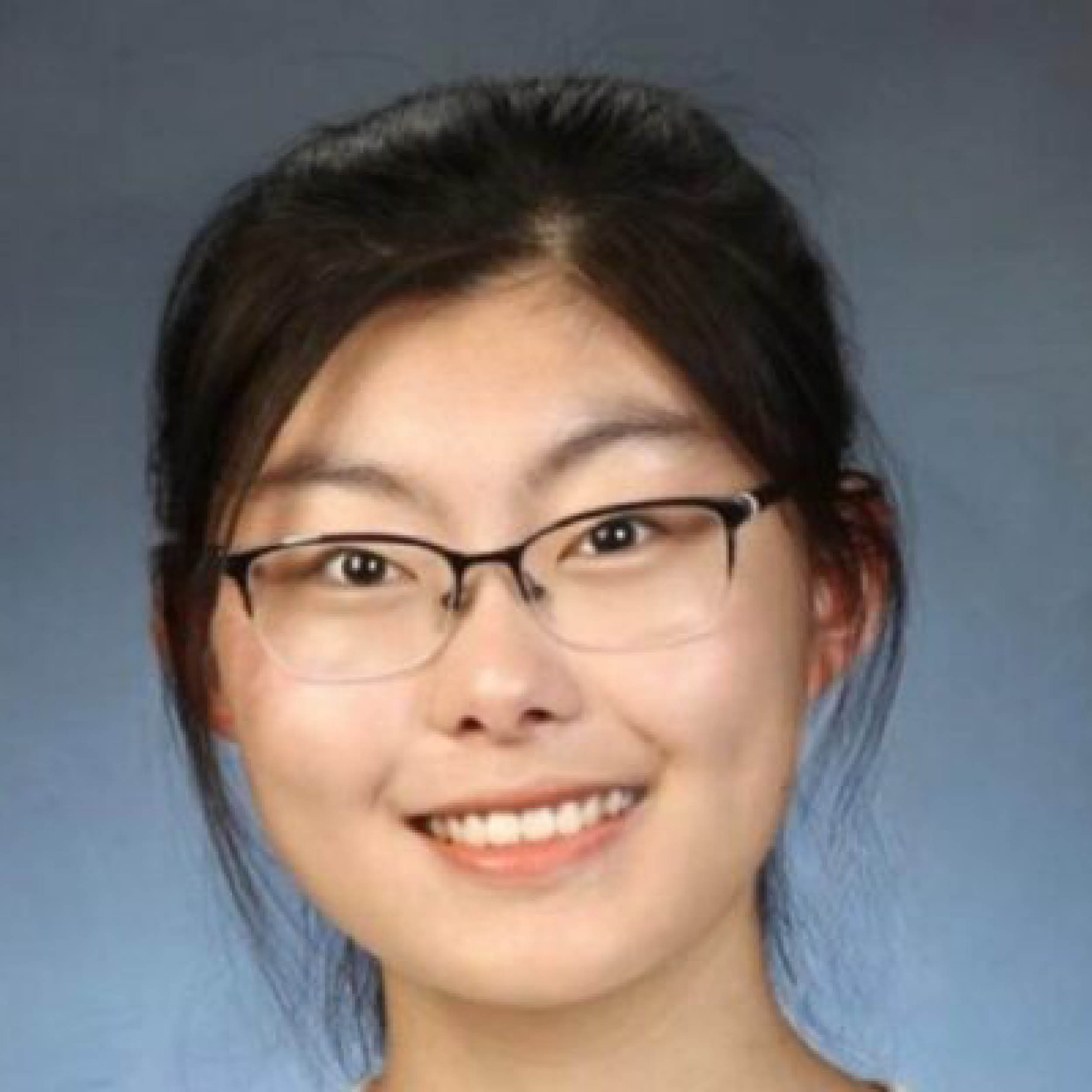 A woman with short dark hair, glasses, and a bright smile.