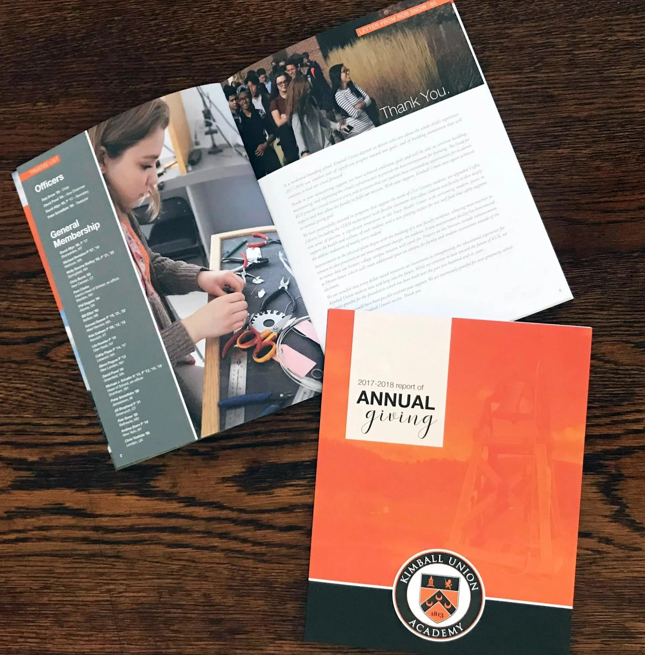 A brochure or program for the 2017-2018 annual giving campaign of Kimbell Union Academy, featuring an image of a group of diverse people standing in line or assembled together, and a partial image of a young girl working on a project or assembling a device, on a wooden surface.